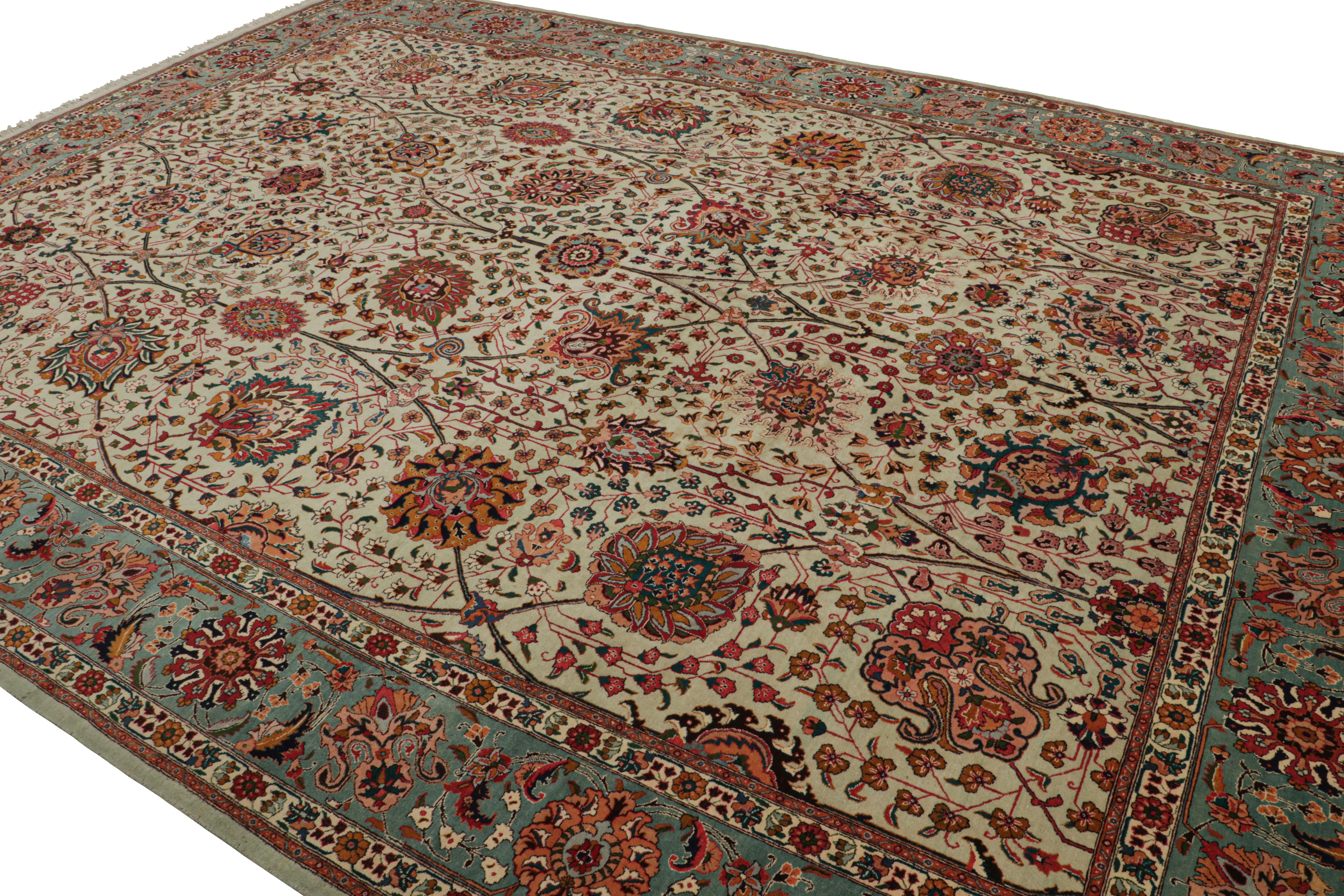 Der handgeknüpfte Wollteppich (ca. 1950-1960) im Format 11x14 aus Täbris zeigt ein dichtes Blumenmuster in einem Spektrum lebendiger Farbtöne, das majestätisch auf einem beigen Hintergrund sitzt und für einen opulenten Look sorgt. Der geschmackvolle