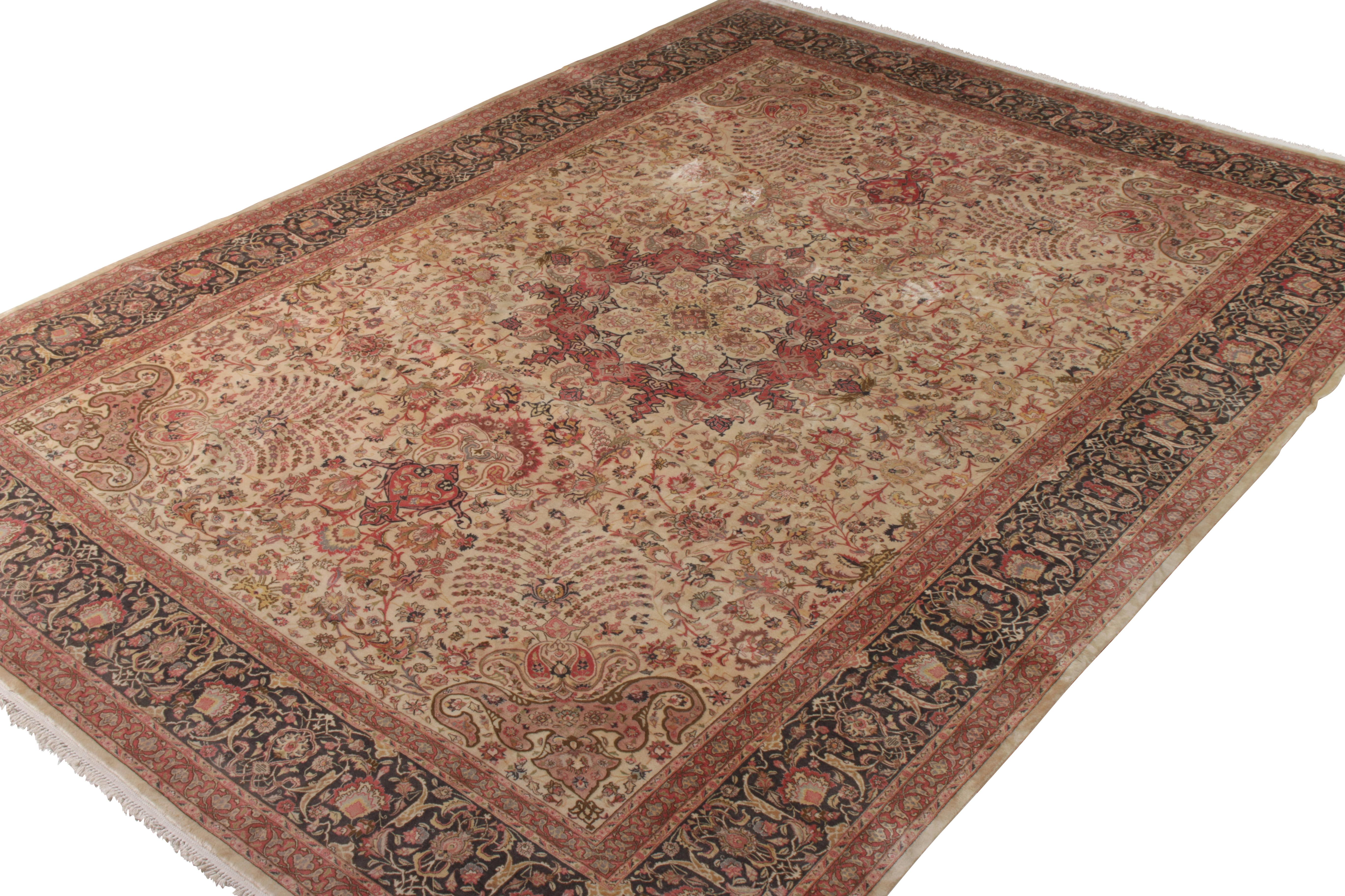 Hand knotted in wool originating circa 1950-1960, this 11 x 15 vintage Persian rug connotes a midcentury Tabriz rug style of fabulous color and regal pattern—hues of pink and red in majestic floral patterns played against beige to enfold a Classic