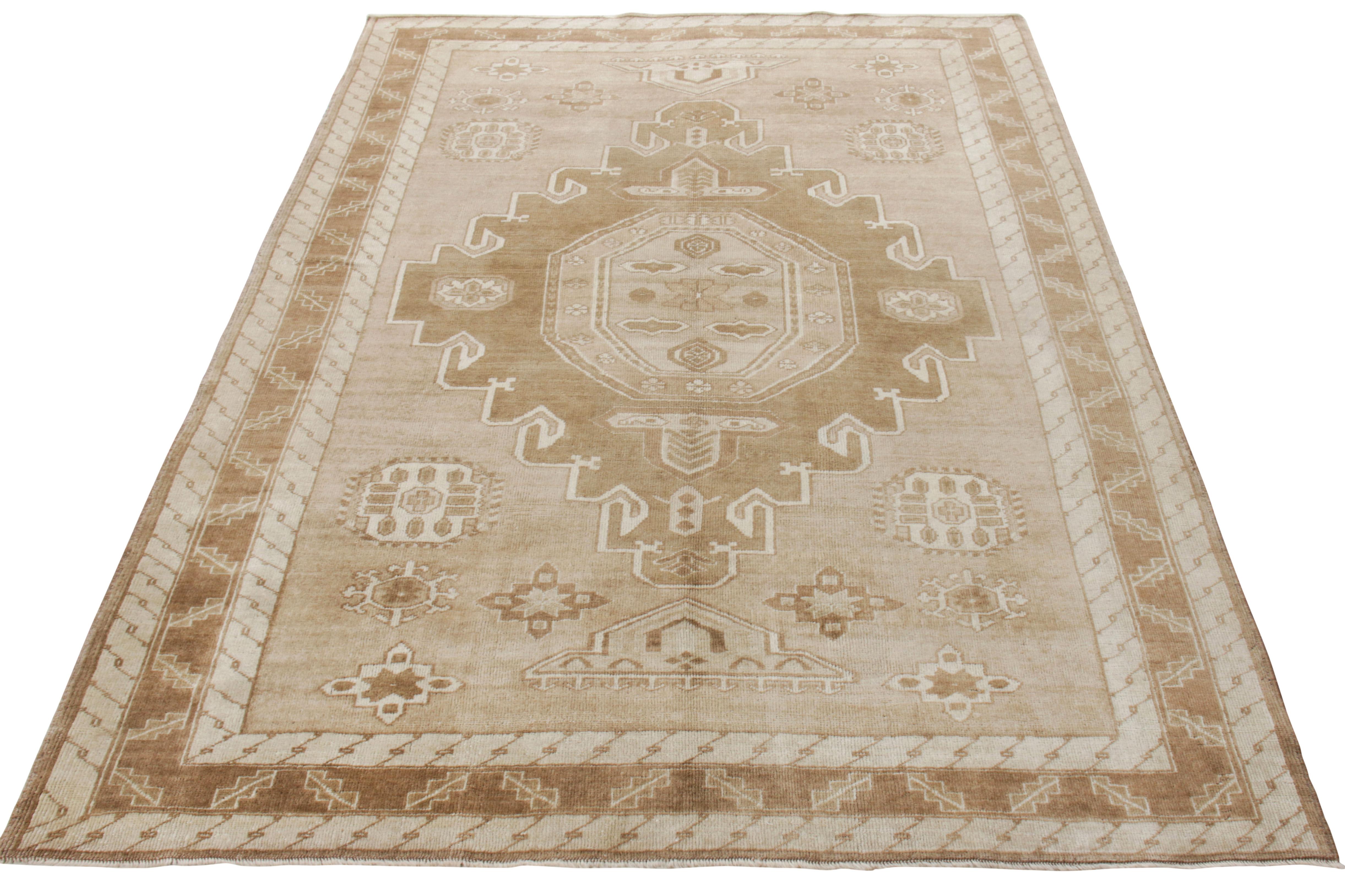 Hand knotted in wool, a vintage Kars rug originating from Turkey circa 1950-1960. This piece defines mid century craftsmanship in its pristine form that enjoys the union of a clean medallion & geometric pattern with muted shades of beige-brown &