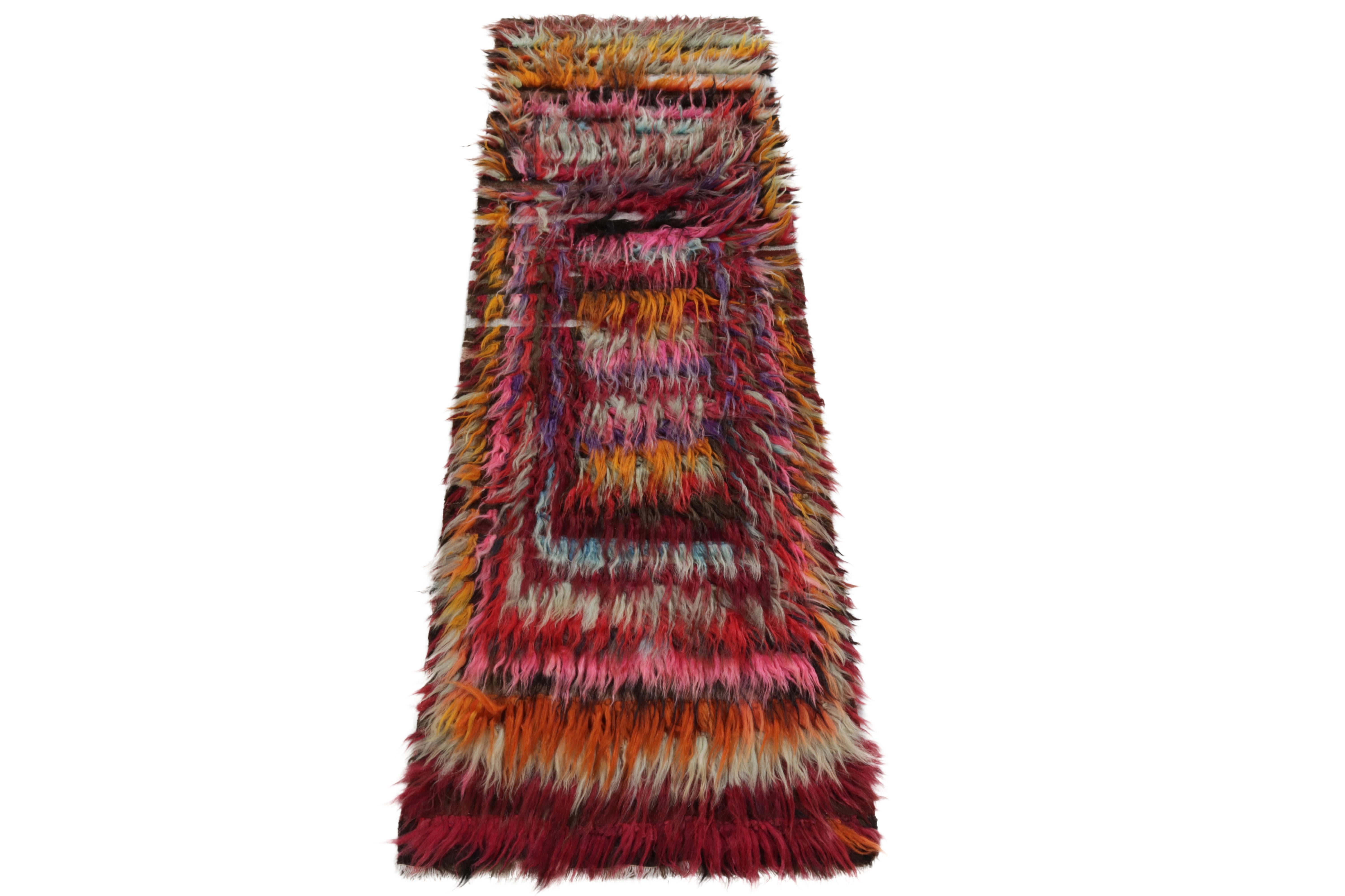From Rug & Kilim’s vintage selections, a hand-knotted Tulu mid-century runner carrying a luscious high pile. Originating from Turkey circa 1950-1960, the 3x9 tribal rug enjoys a geometric pattern in hues of red, pink, orange, yellow, lavender &