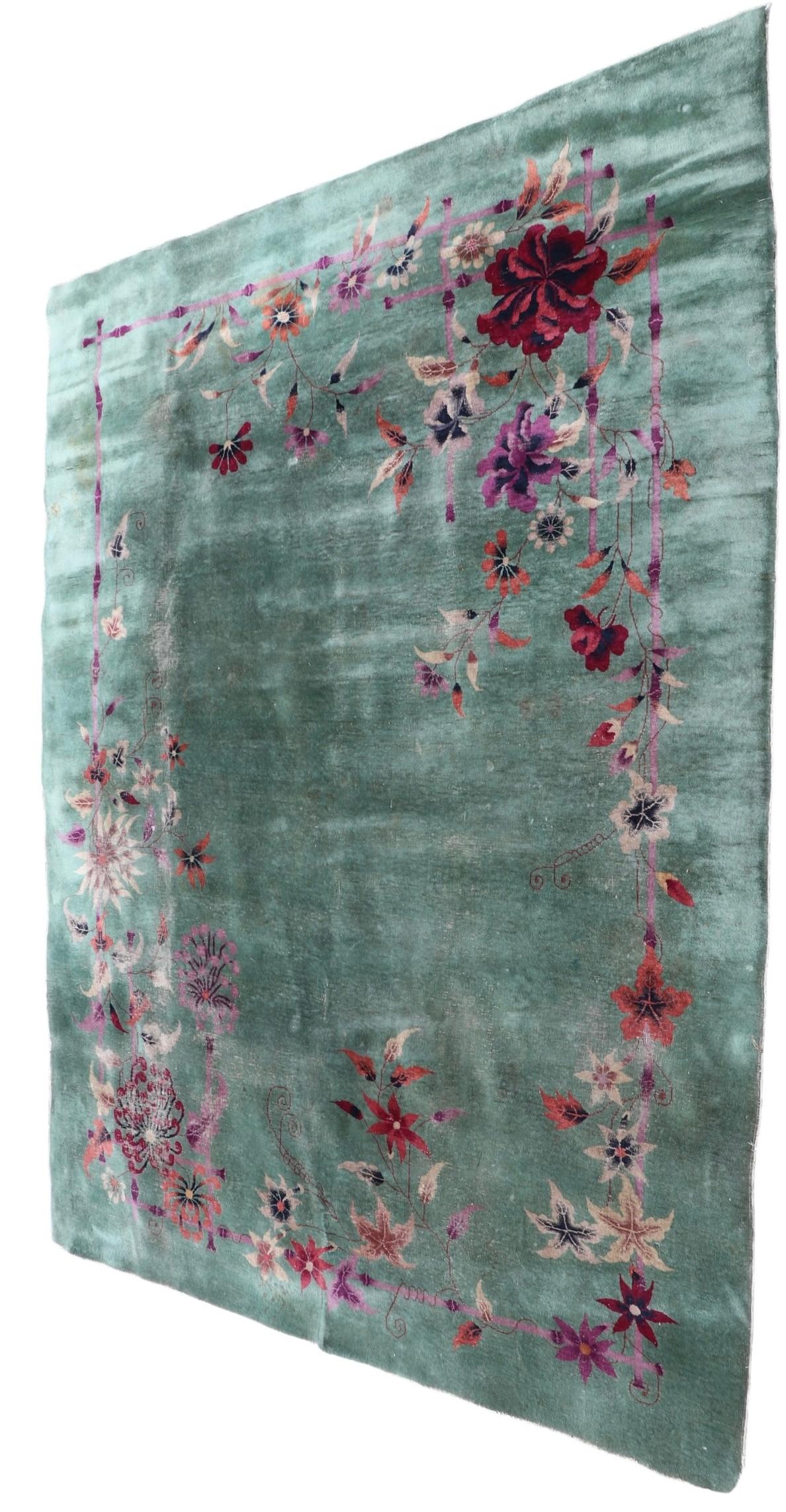 Dekorativer chinesischer Art-Déco-Teppich aus handgeknüpfter Wolle, im Stil von Nichols. Der Teppich hat einen grünen Grund mit dekorativem Blattwerk, das mit einer unerwarteten lavendelfarbenen Bambusbordüre verflochten ist. Dieses Exemplar