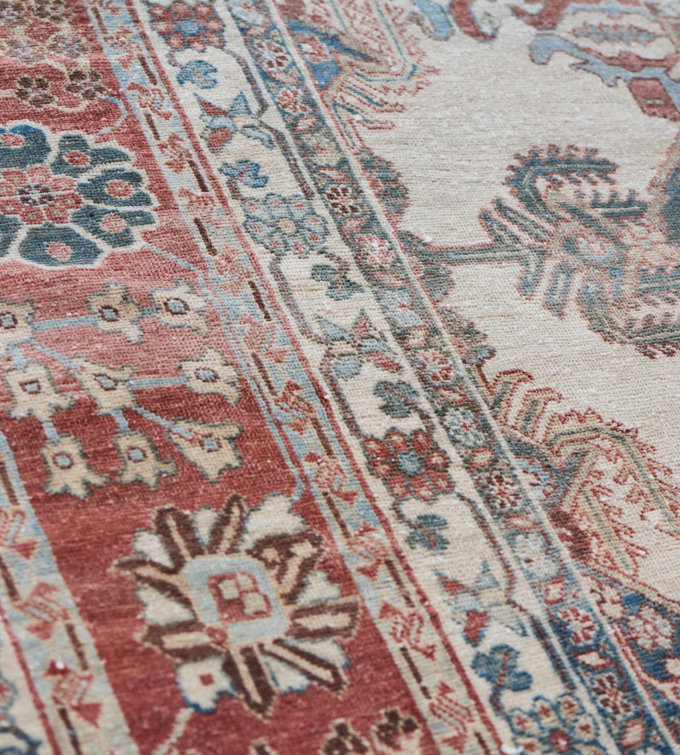 Cet ancien tapis persan Bakhtiari présente un champ ivoire avec des rangées diagonales de losanges et de parties de losanges bleu ciel nuancés, chacun contenant un motif floral central rouge brique et ivoire, les losanges étant entourés de parties