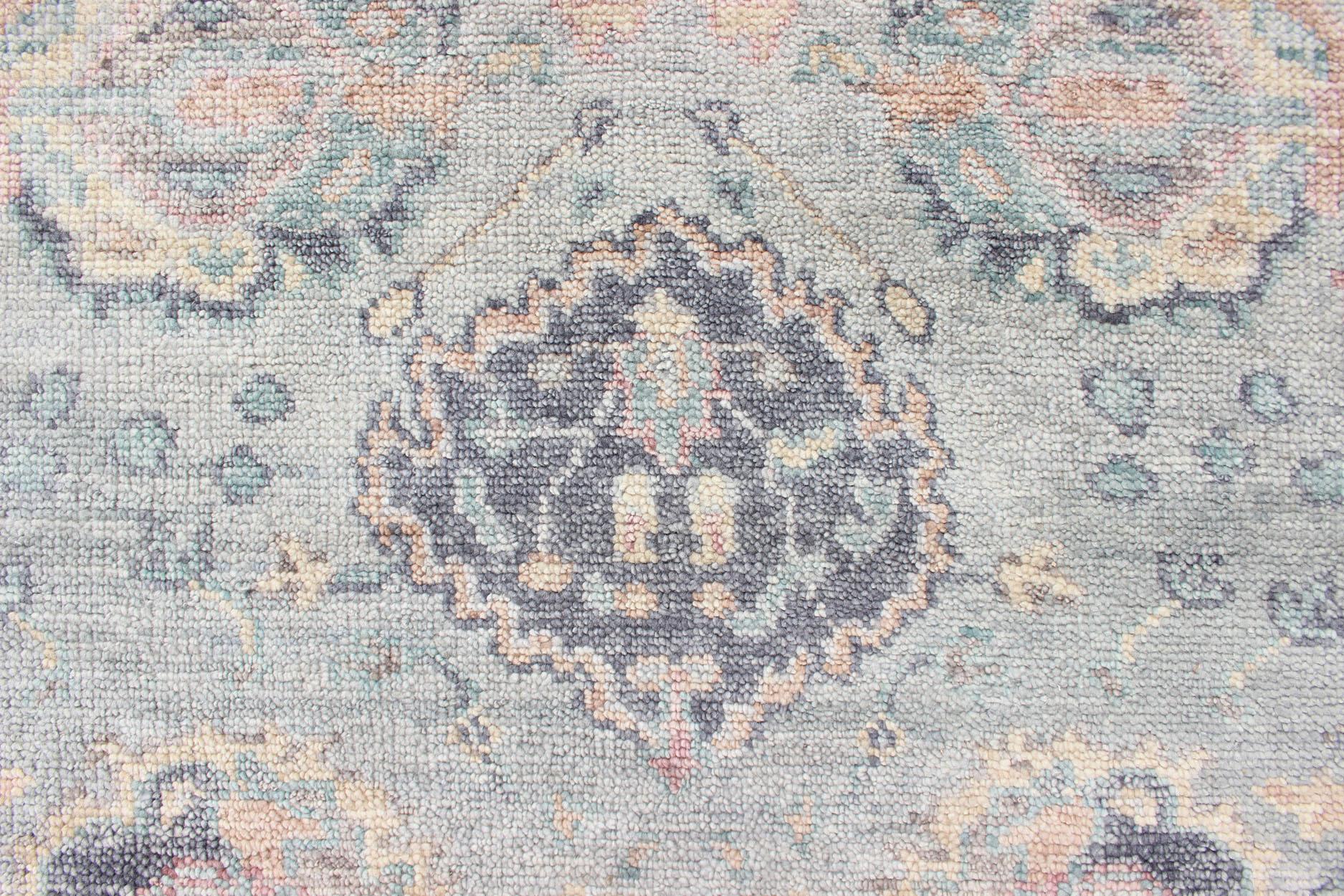 Hand Knotted Wool Oushak Rug Featuring Floral Designs in Muted Colors.
Measures 7'8 x 9'9 
This Indian Oushak was hand-knotted with wool during the 2010's. The muted color palette features like blue, green, orange, and peach. This Oushak displays