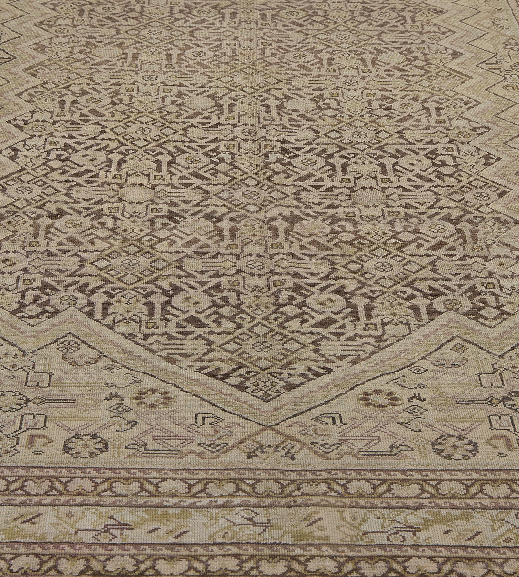 This antique Malayer rug has a mole-brown field with a sandy-yellow and pistachio-green angular herati-pattern, the sandy-yellow inked spandrels with an angular floral and serrated leaf vine with a bold zig-zag outer band stripe, in a sandy-yellow