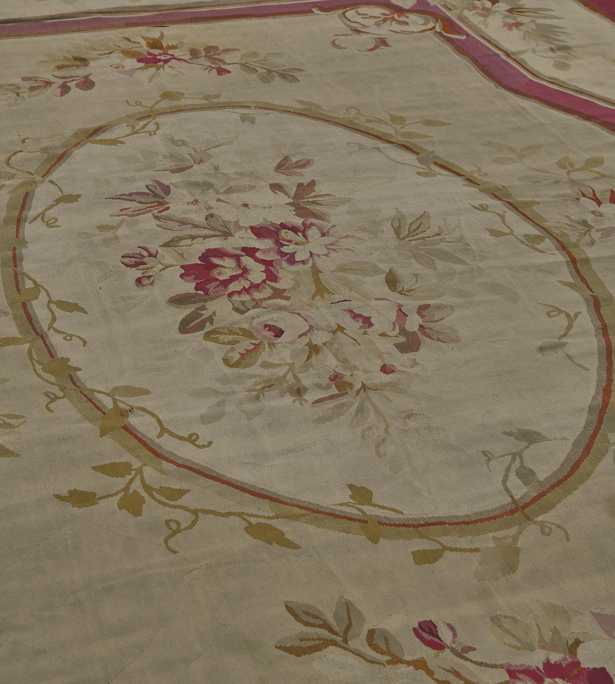 Questo antico tappeto Aubusson a tessitura piatta presenta un campo in eau-de-nil con un ovale centrale in avorio contenente un grande spruzzo floreale e frondoso all'interno di una stretta fascia verde sfumata e rosso lampone intrecciata con una