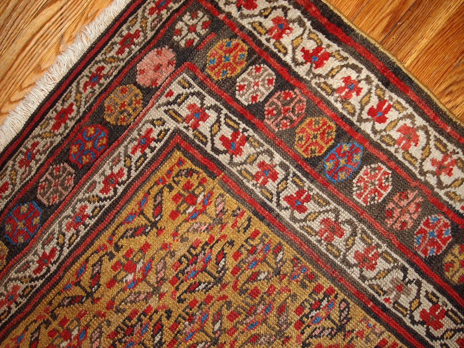 Alfombra antigua de estilo kurdo en colores amarillo, blanco y rojo. La alfombra es de finales del siglo XIX, en buen estado. Medidas: 125 cm x 235 cm (4,1' x 7,7').
