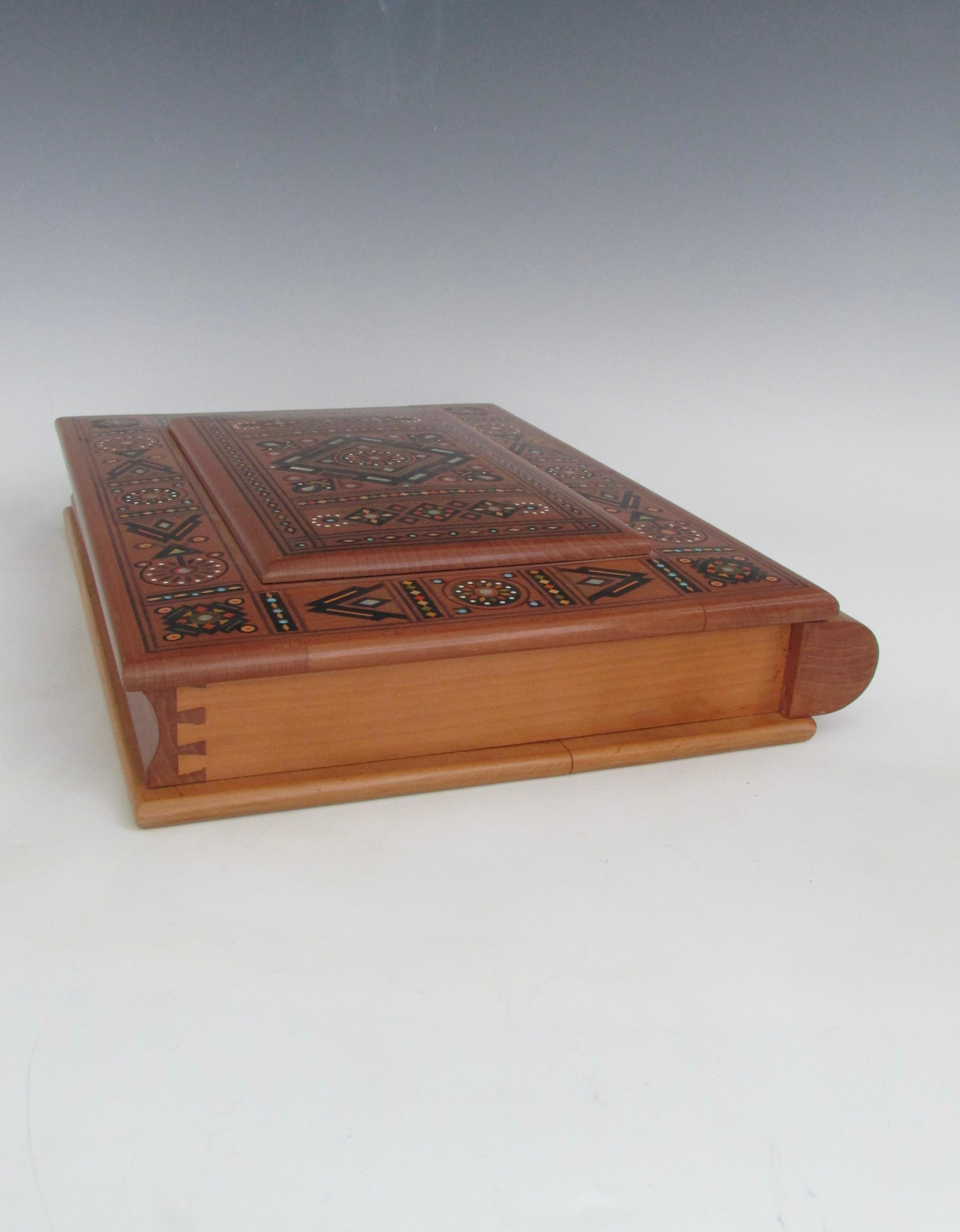 Beautifully made keepsake box. Hinged lid and spine are intricately inlaid with mother of pearl, exotic wood, beads. Backside has pyrographic image burned in. All nicely joined with dovetail detail. Not sure on country of origin. Backside image does