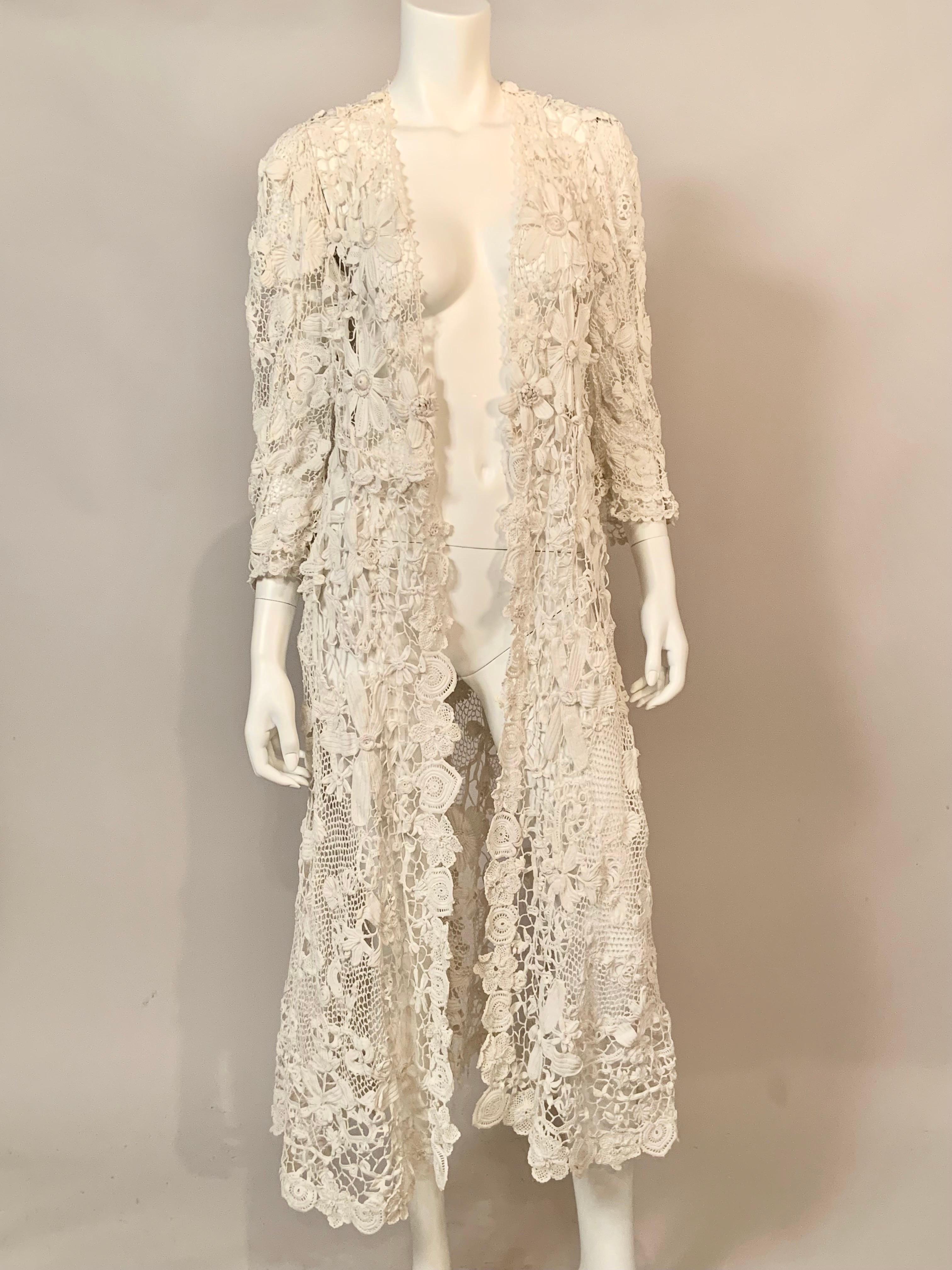 This handmade Irish lace coat has an unusual border pattern of large scale flowers and leaves which runs all the way down the center front and around the hemline. The bodice of the coat, front and back, is also hand made with large motifs.  The body