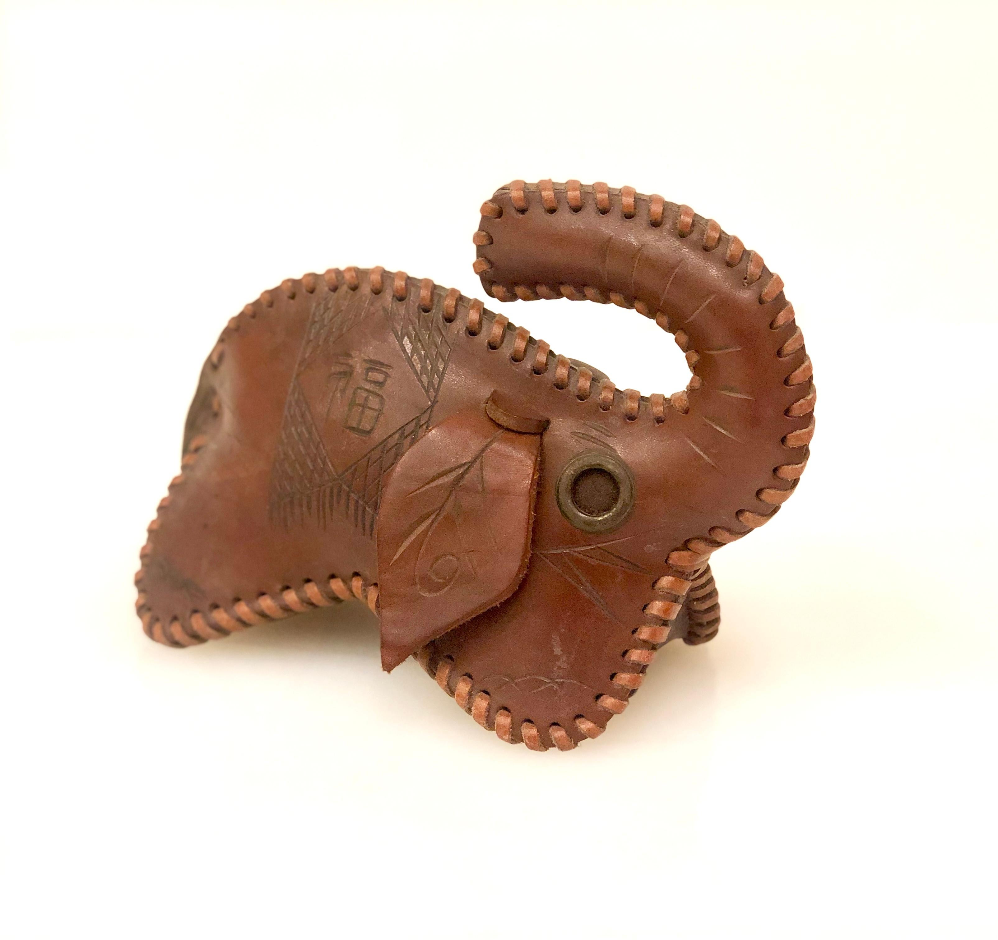 A rare and unique leather elephant toy or decorative object, with handstitched leather cord, and engraving on the sides as shown, metal rings as eyes well done piece filled inside.