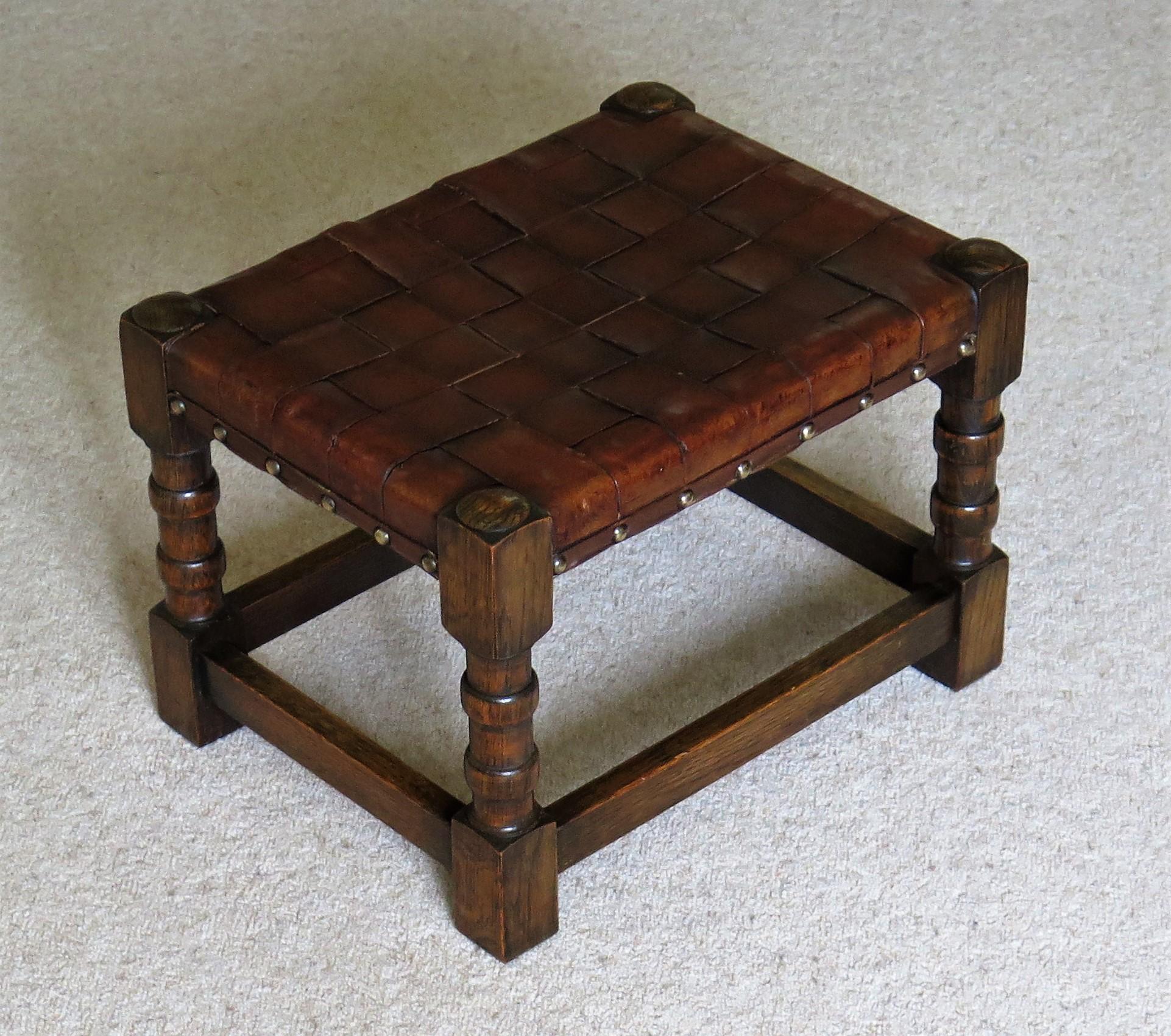 This is a good handmade stool with a well turned solid oak frame and a woven leather strap top, all dating to the Arts & Crafts period of the late 19th century.

The stool is made of solid oak. The frame joints into four legs with ring turned