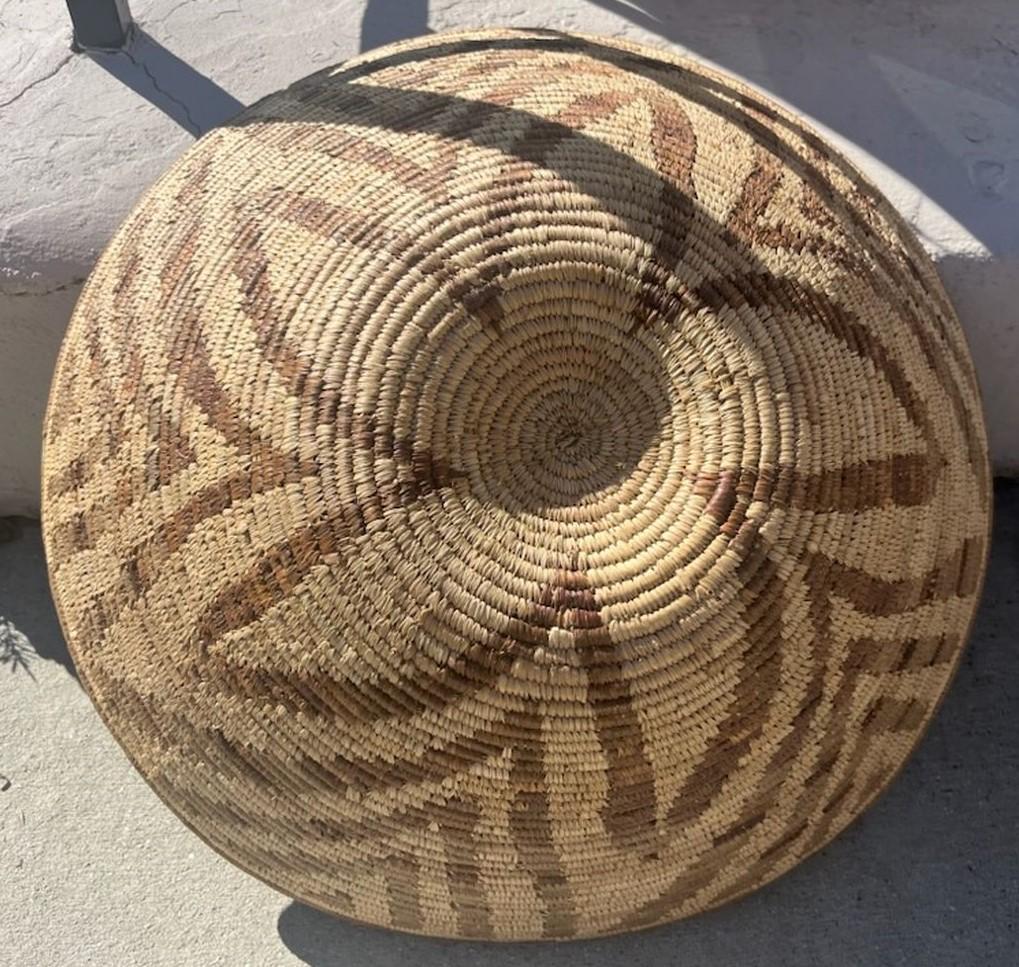 Cesta india Papago hecha a mano con diseño floral geométrico. El dibujo fluye en dirección descendente desde la parte superior para mostrar el hermoso motivo floral hacia el centro de la cesta. La cesta está hecha con una hierba del diablo y está en