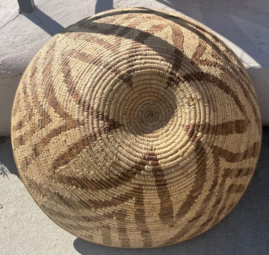 Panier indien Papago fabriqué à la main avec un motif floral géométrique. Le motif s'écoule du haut vers le bas pour laisser apparaître le magnifique motif floral vers le milieu du panier. Le panier est fabriqué à partir d'une herbe du diable et est