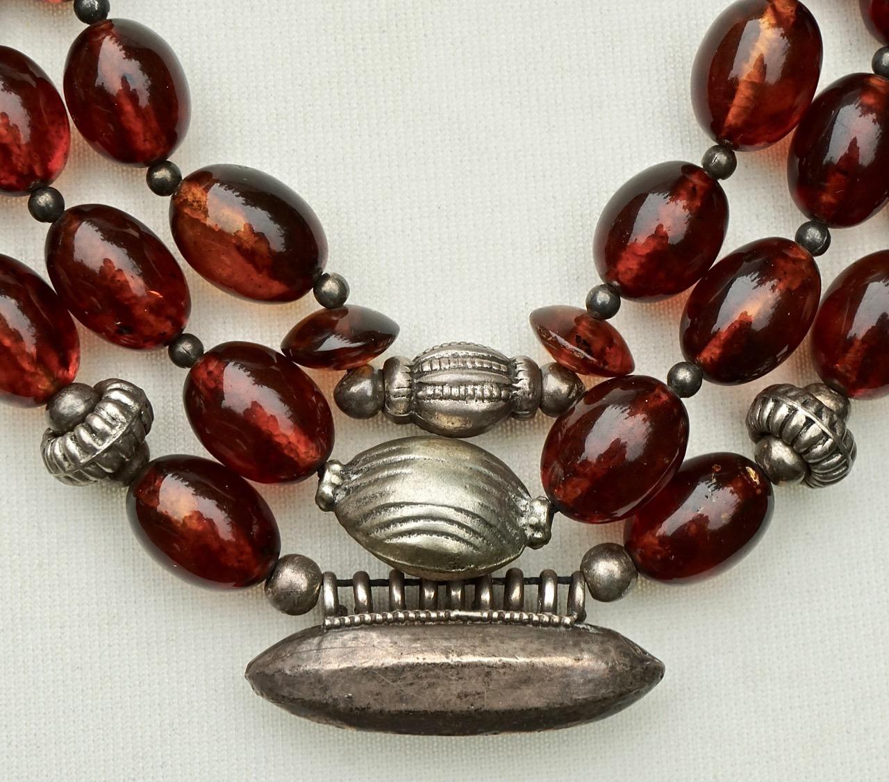 Hand made decorative silver tone necklace with beautiful polished cognac amber beads, and a simple hook clasp. The first strand has two lighter amber beads and disk shaped beads. They are strung on black thread, which is a little loose at the ends,