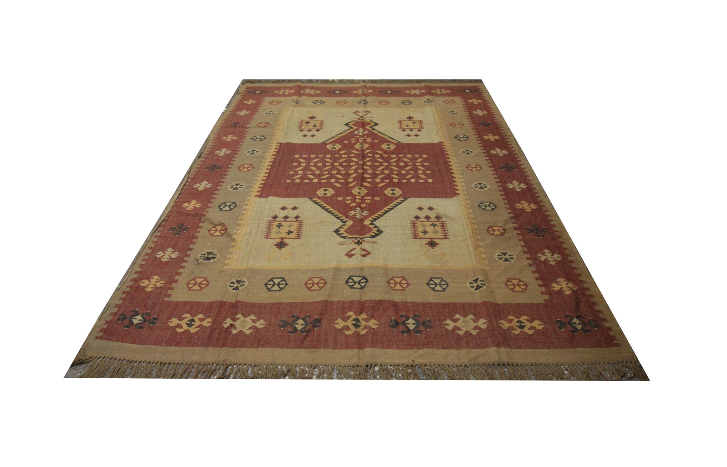 This traditional Indian Kilim area rug features muted neutral tones of beige, brown and Burgandy, the central medallion is a geometric emblem with further details interwoven in the center. This design is then enclosed by a detailed repeat pattern