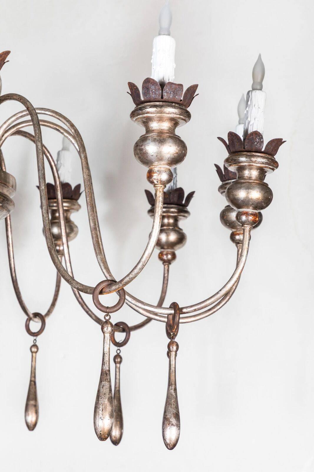 Twelve-light, carved-wood and metal Tuscan chandelier with tear-drop embellishments, in a gessoed and silver gilt finish.
