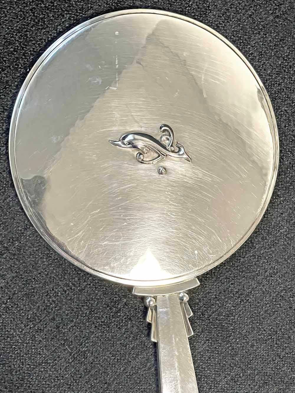 An iconic Art Deco design, crafted in sterling silver by Harald Nielsen for George Jensen -- arguably the most renowned silversmith in the world at the time -- this hand mirror features a sleek, streamlined form and a delightful dolphin form on the