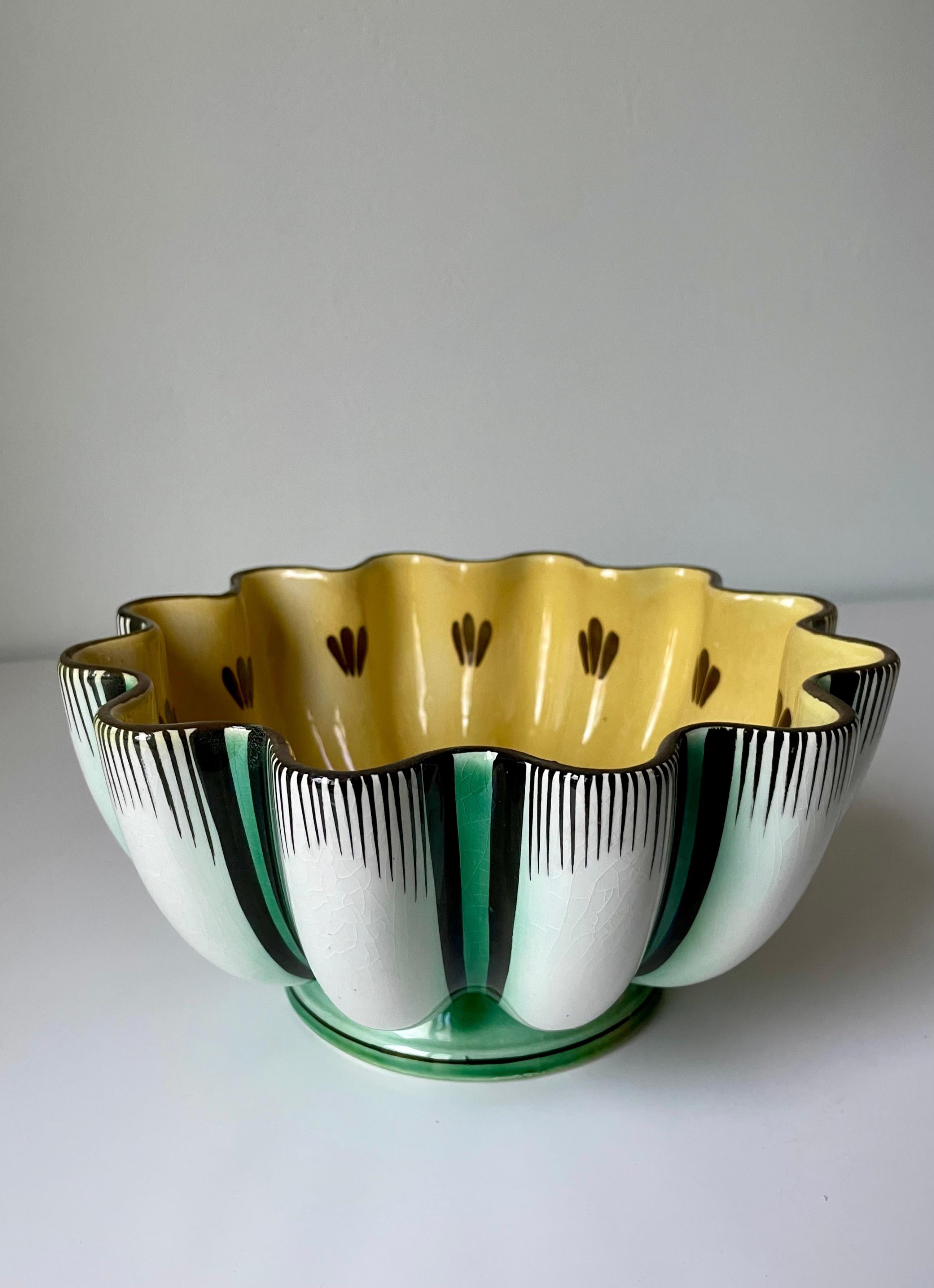 Swedish art deco bowl with wavy edge designed by Arthur Percy and hand-decorated by Eugen Trost for Gefle in the late 1920s-early 1930s. Hand-painted geometric, stylized, lined decor in white, green, black, yellow and caramel brown colored glaze.