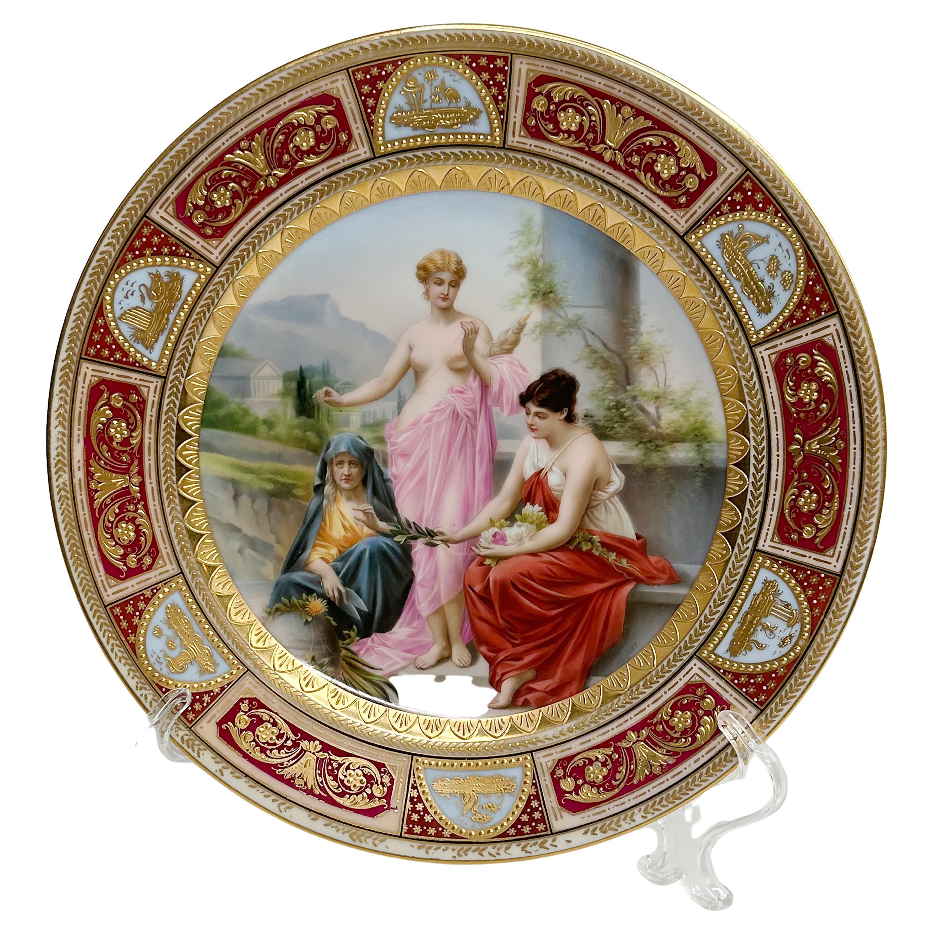 A beautifully hand painted and gilt porcelain cabinet plate. This is a reproduction of a depiction of Die Parzen (The Three Fates). Of the Imperial Viennese period. Likely made in Germany per the marking on the back. Acrylic stand not