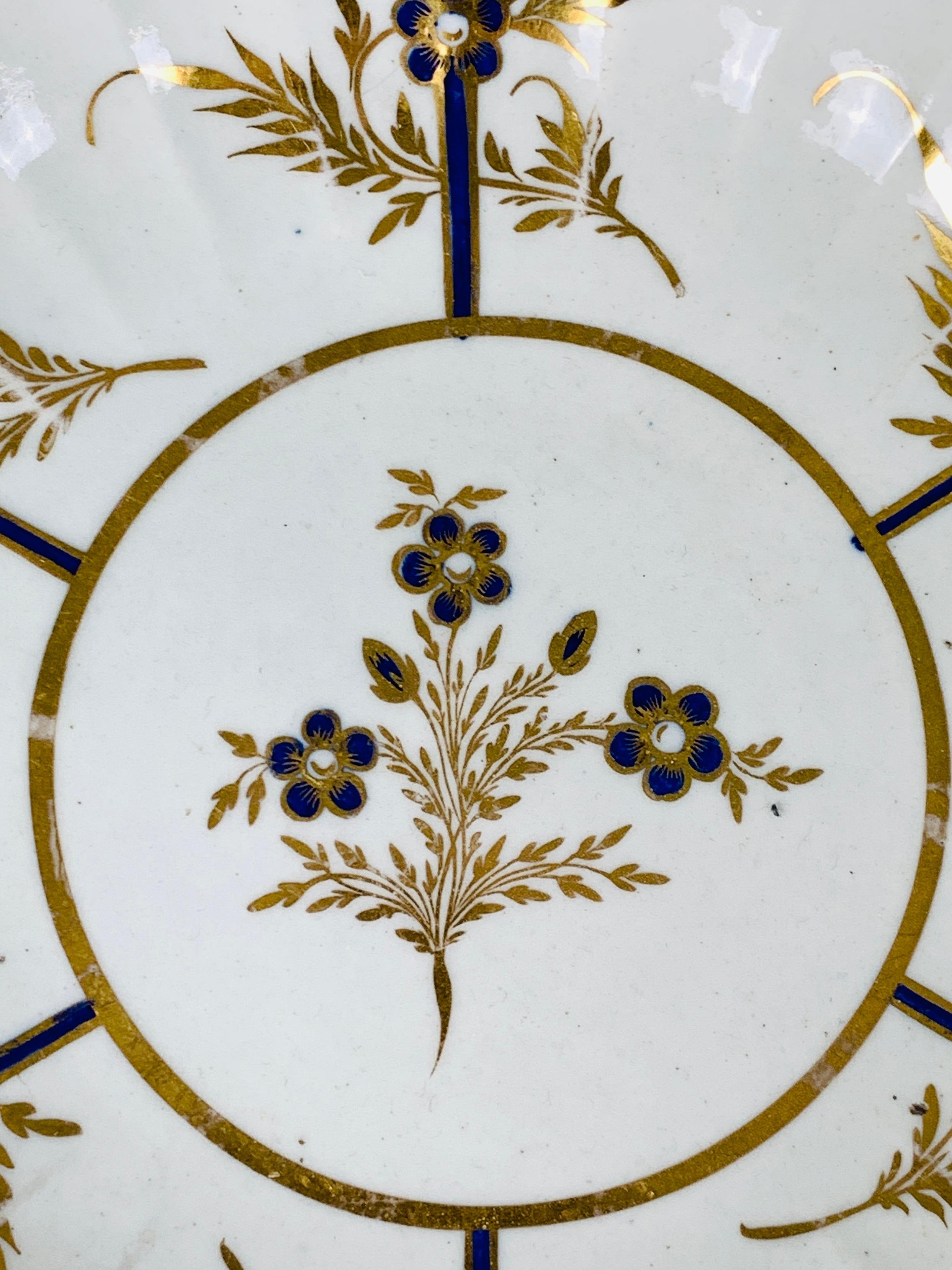 This exquisite late 18th-century dish features several elements that make it so full of life.
First is the splendid hand-painted goldwork. 
This gilding enlivens the dish with its hand-painted golden vines, leaves, and edge. 
Additionally, the