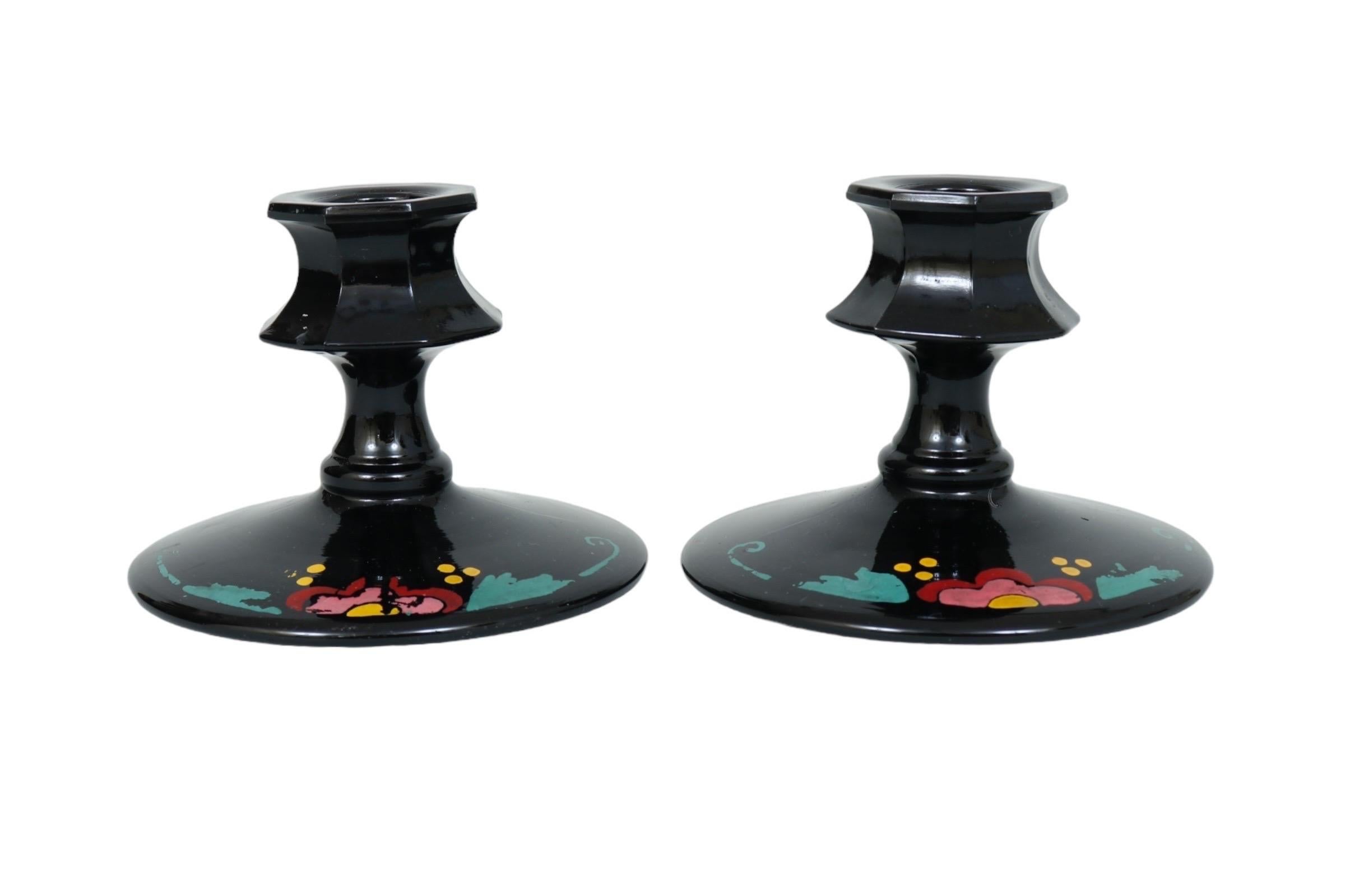 Coppia di portacandele in vetro nero dipinto a mano. Le appliques ottagonali poggiano su brevi colonne tornite sopra basi rotonde, ornate da un semplice fiore colorato. Dimensioni per portacandele.
