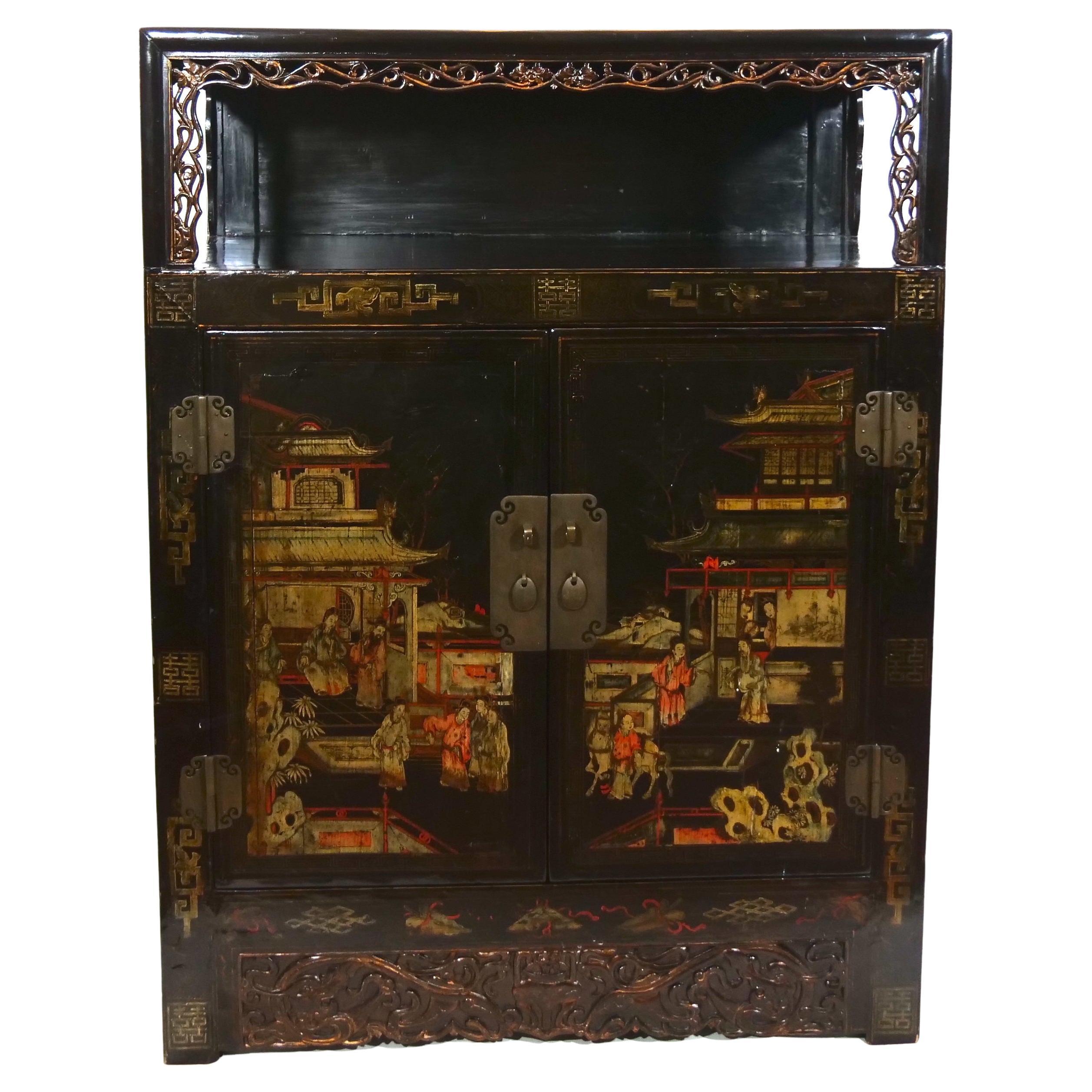 Early 20th century hand painted black lacquered wood two piece chinoiserie display cabinet. The cabinet features a removable trunk top with different hand painted chinoiserie scene, two front door and a hidden secret compartment resting on four
