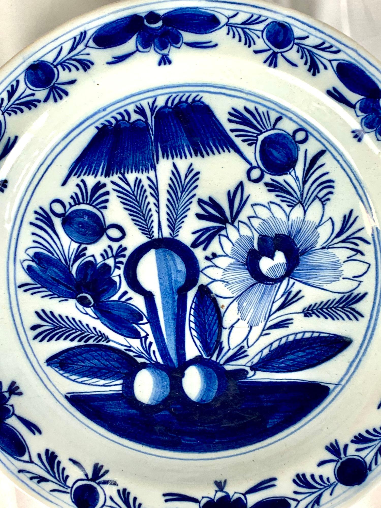 This blue and white Delft charger was hand painted in the Netherlands circa 1800.
The center features a garden scene with beautiful flowering peonies.
We see blossoming flowers, buds, leaves, and rockwork.
The wide border shows a lovely repeating