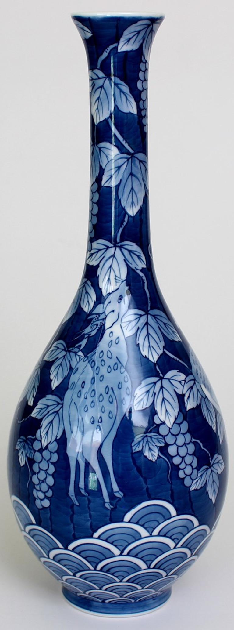 This hand painted contemporary porcelain vase created by an artist of the Imari-Arita region of Japan depicts a peaceful scene of deer at play in solid cobalt blue. The artist is the recipient of numerous awards for his signature gold and platinum