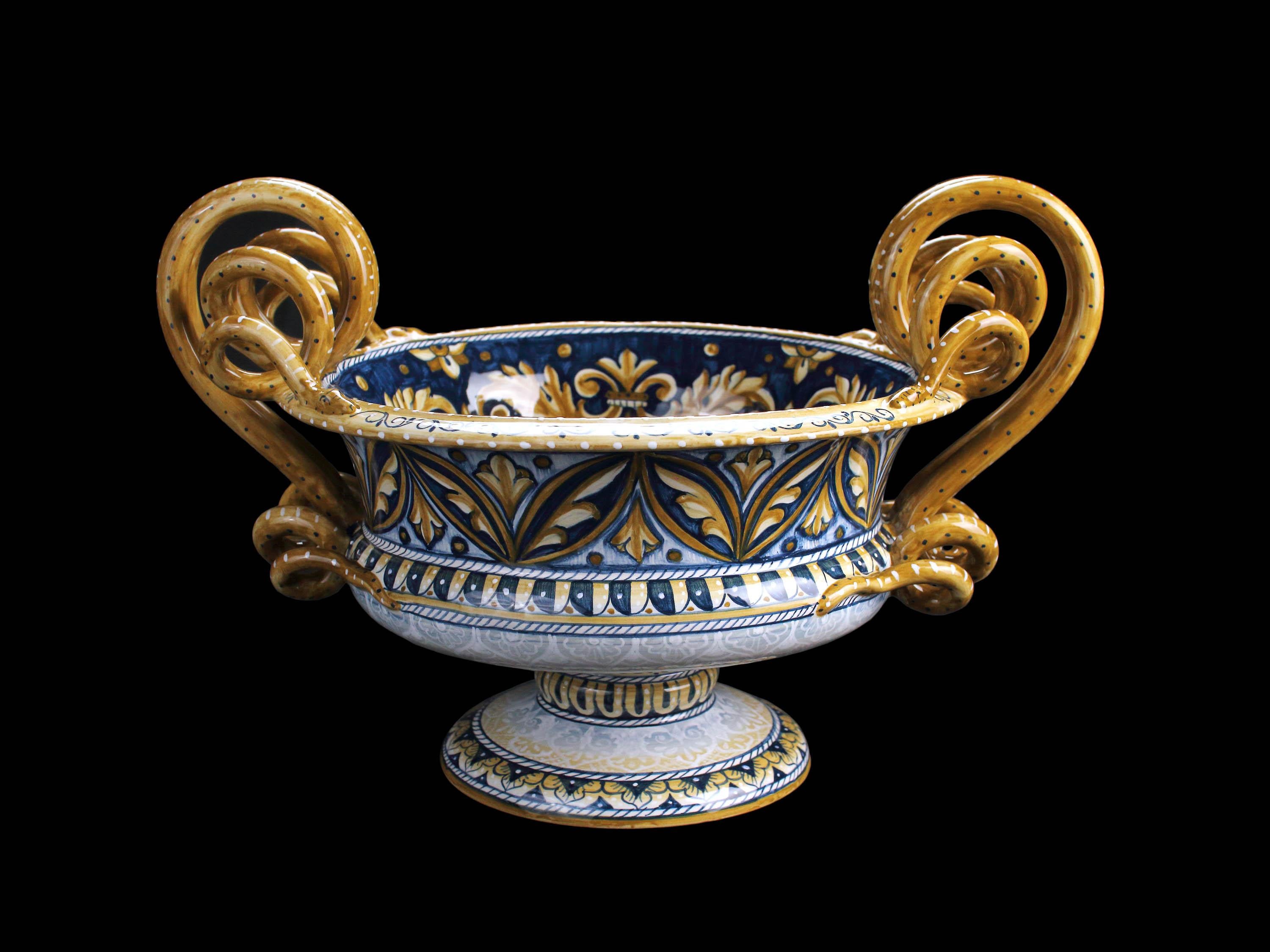 This fine majolica centerpiece is made and hand-painted in Deruta, Italy. The Bowl recalls the ancient structure of the Greek cups that were used to mix water and wine, while its decoration reinterprets the opulent ornaments of Deruta tradition,