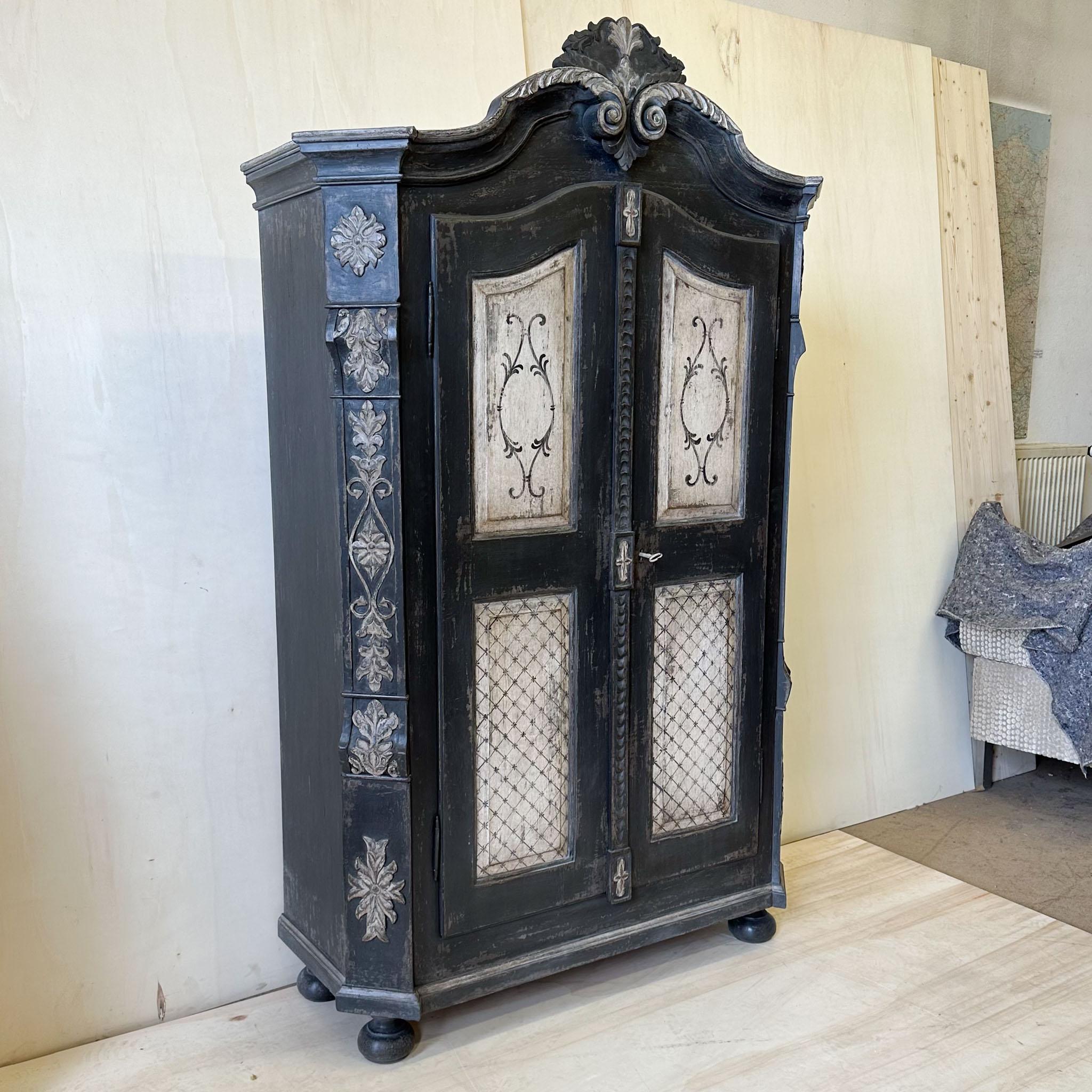 Hand painted two-door cabinet with curved pediment and bevelled corners with carved decoration. The frame in light and dark grey is new and has been decoratively patinated.