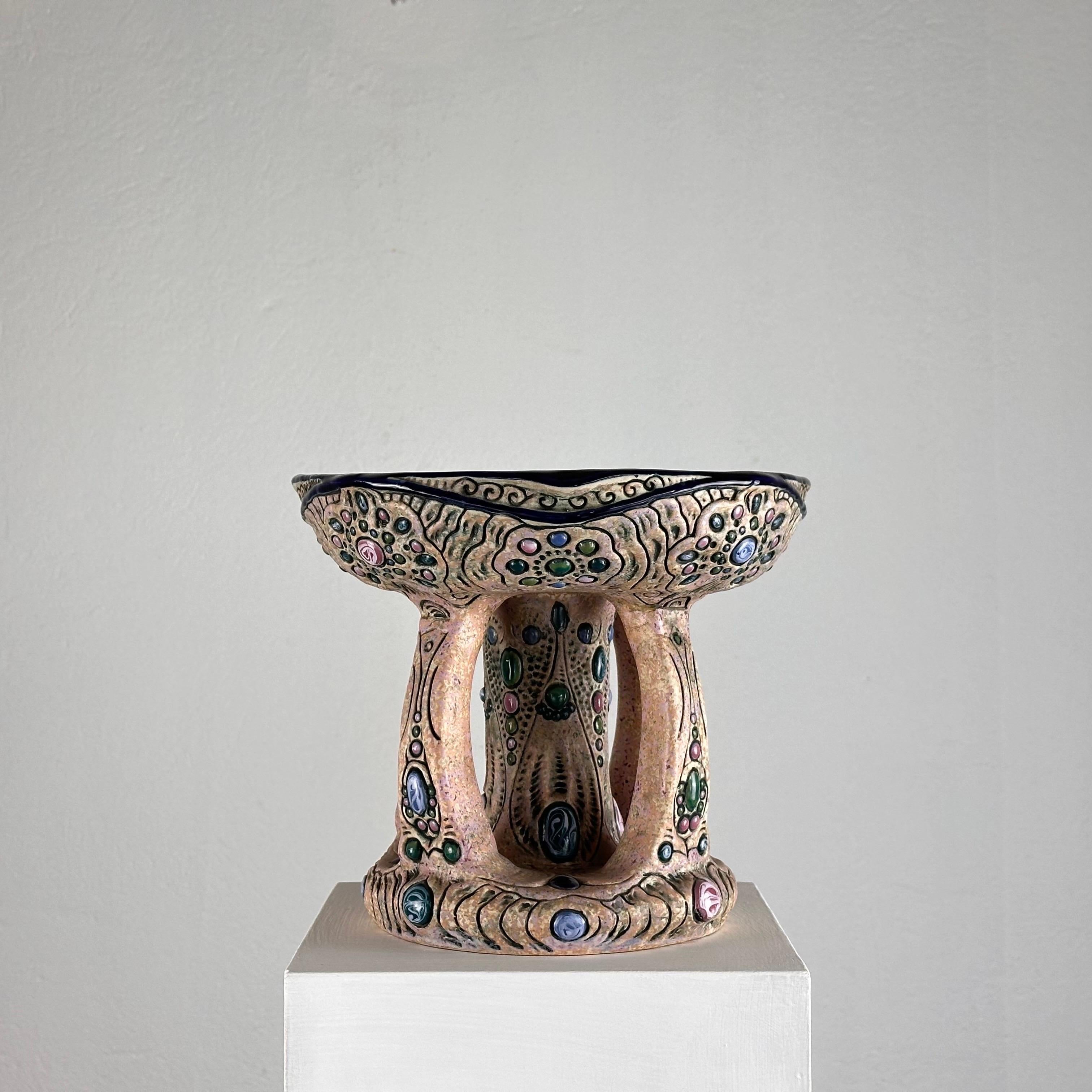 A stunning hand-painted ceramic riser hailing from the renowned Amphora Czech workshops. Crafted with precision and adorned with exquisite hand-painted gem accents, this riser exudes opulence and timeless elegance.

Dating back to the 1930s, this