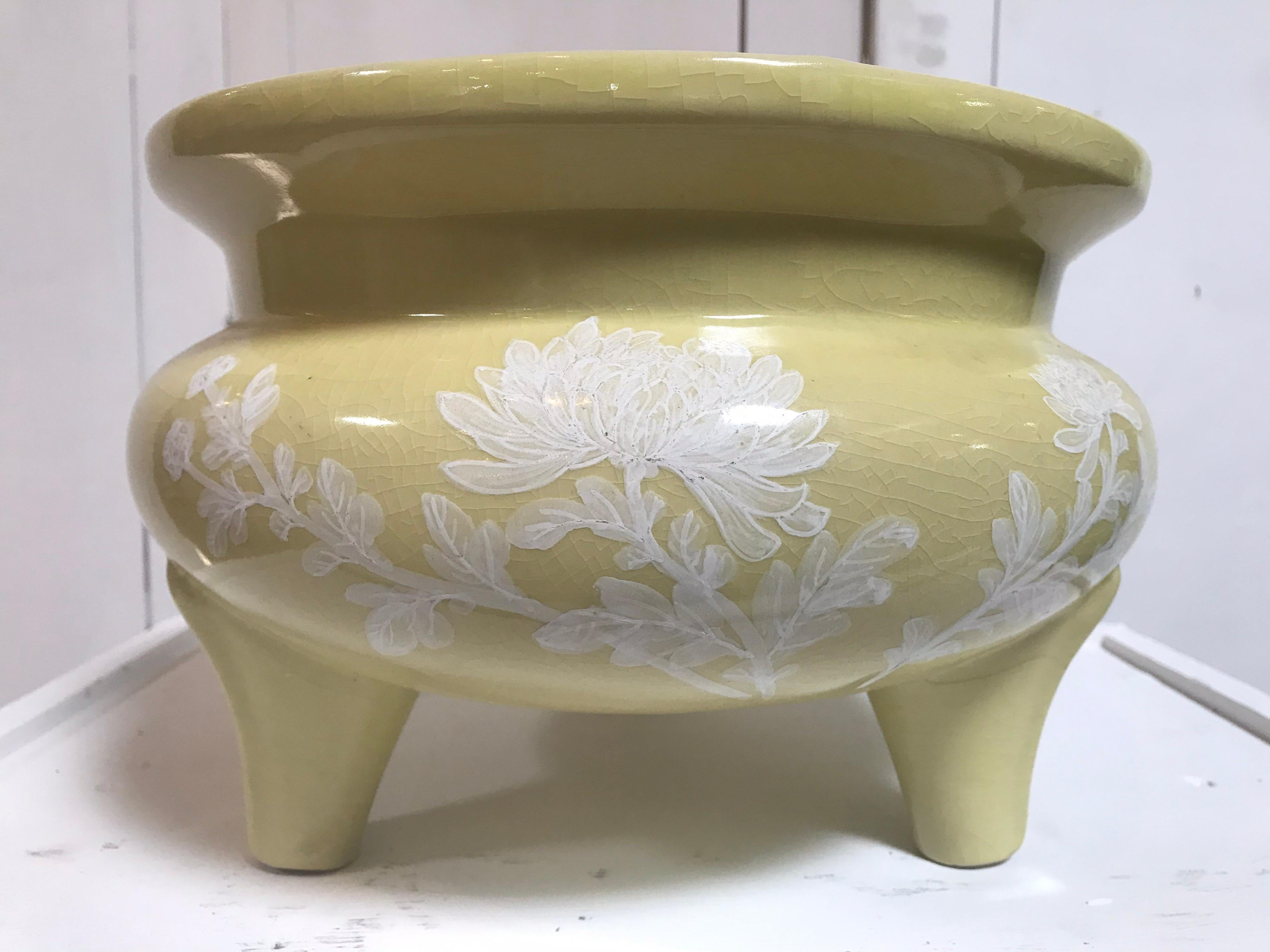 This three-legged Chinese ceramic bowl was dipped in a muted Chartreuse, fired, and then was hand-painted with beautiful white flowers and plants.