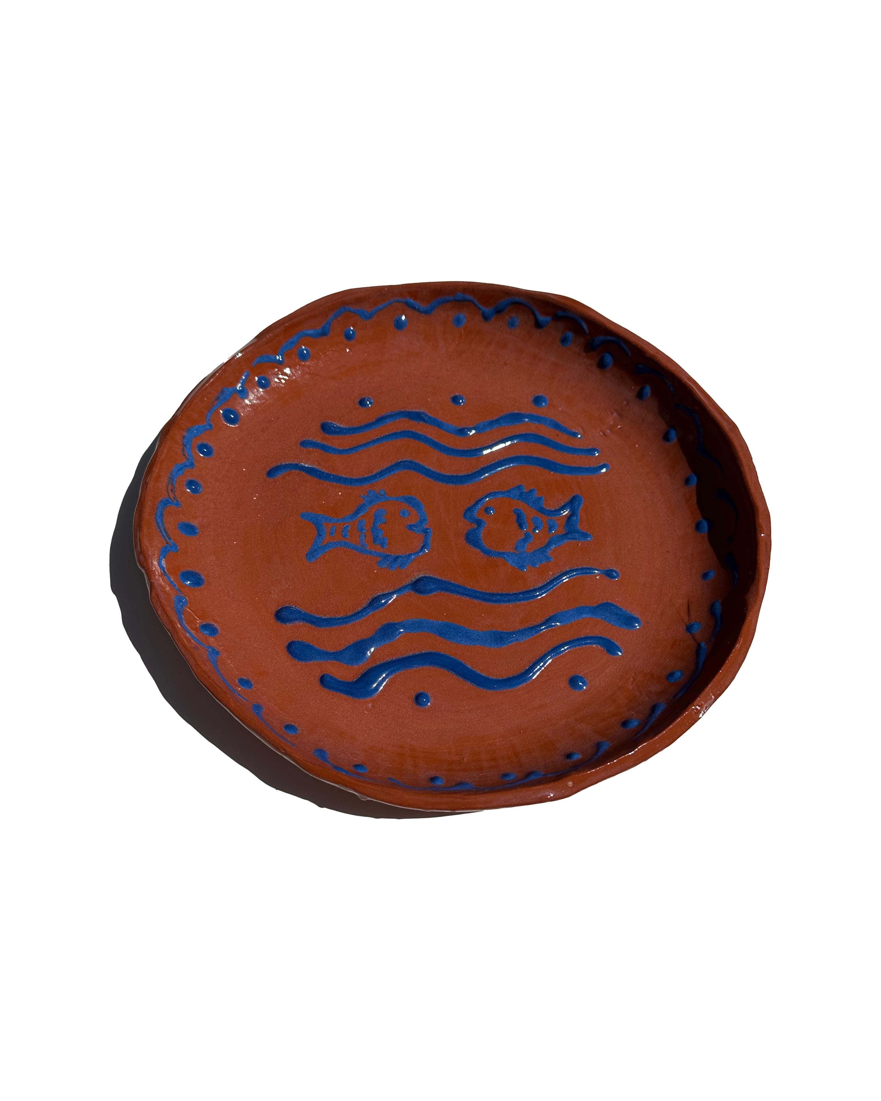 Capture the essence of European summer in your dining space with this hand-painted ceramic serving plate. Boasting a rustic brown base enhanced with cobalt blue scalloped details, this piece beautifully evokes the vibrant seaside ambiance