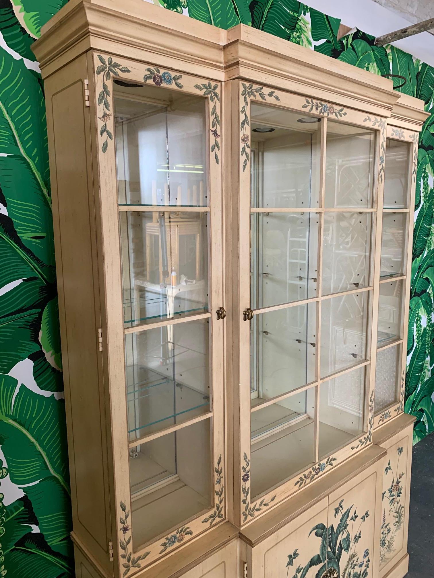 Vintage Drexel china cabinet features hand painted banana leaf detailing and mirrored back. Glass shelving and ample storage below. Very good vintage condition with minor imperfections consistent with age.