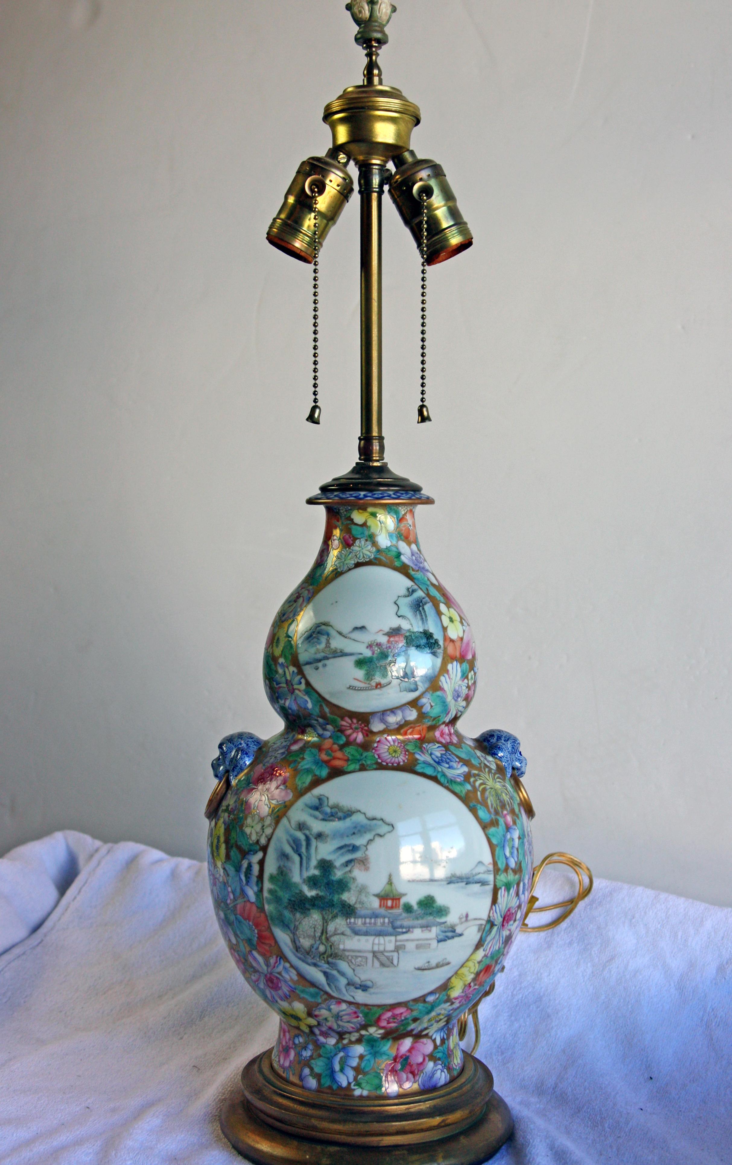 Beautifully hand painted Chinese double-gourd lamp. Sits on a wood base with a carved ornamental finial. Shade included.
