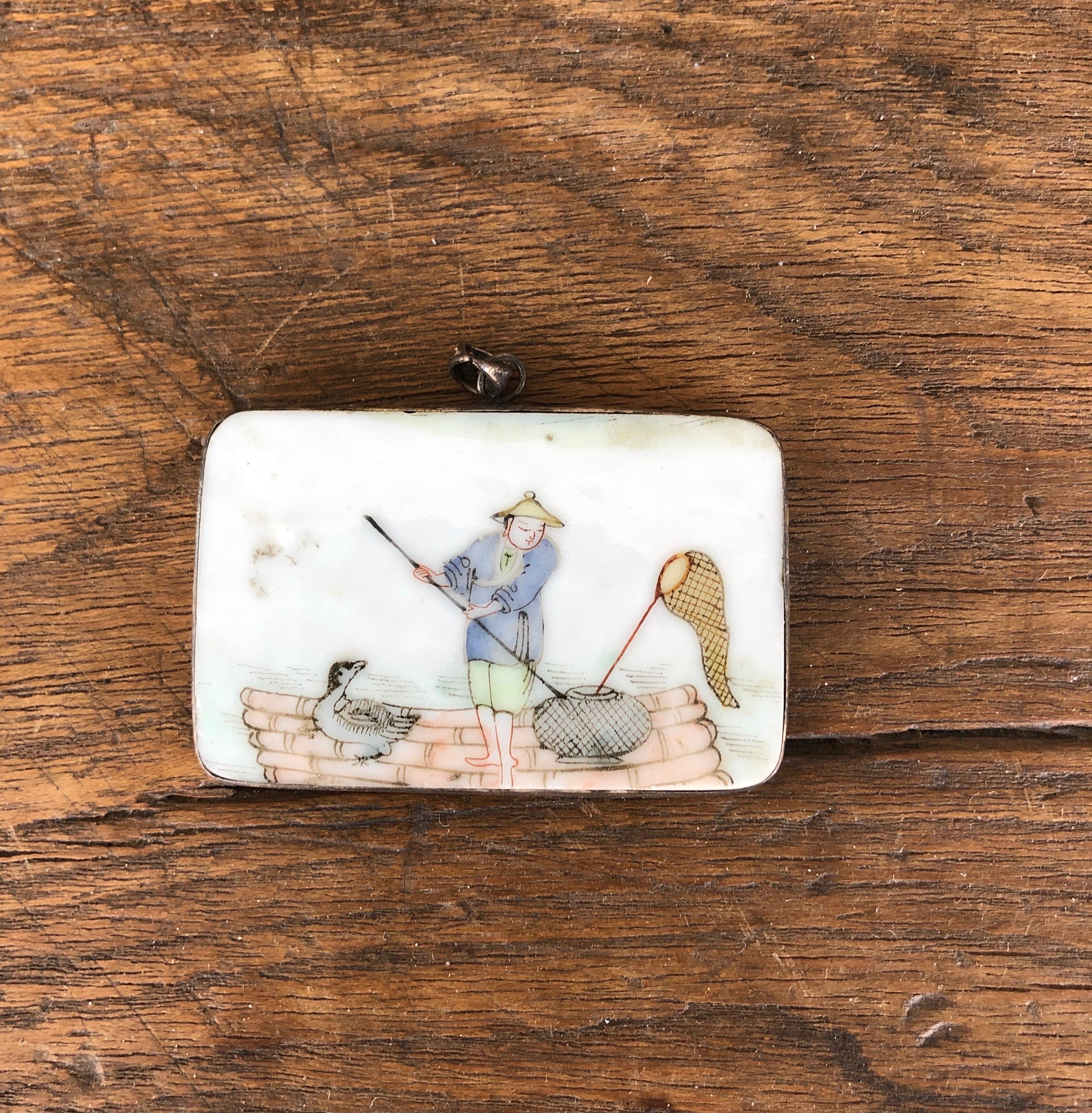 A small, intricately  hand painted Chinese porcelain  pendant, with extraordinarily detailed tiny images of a fisherman tending his basket and net.  The skill required for this delicate tiny brushwork cannot be overstated.  A really sweet piece, and