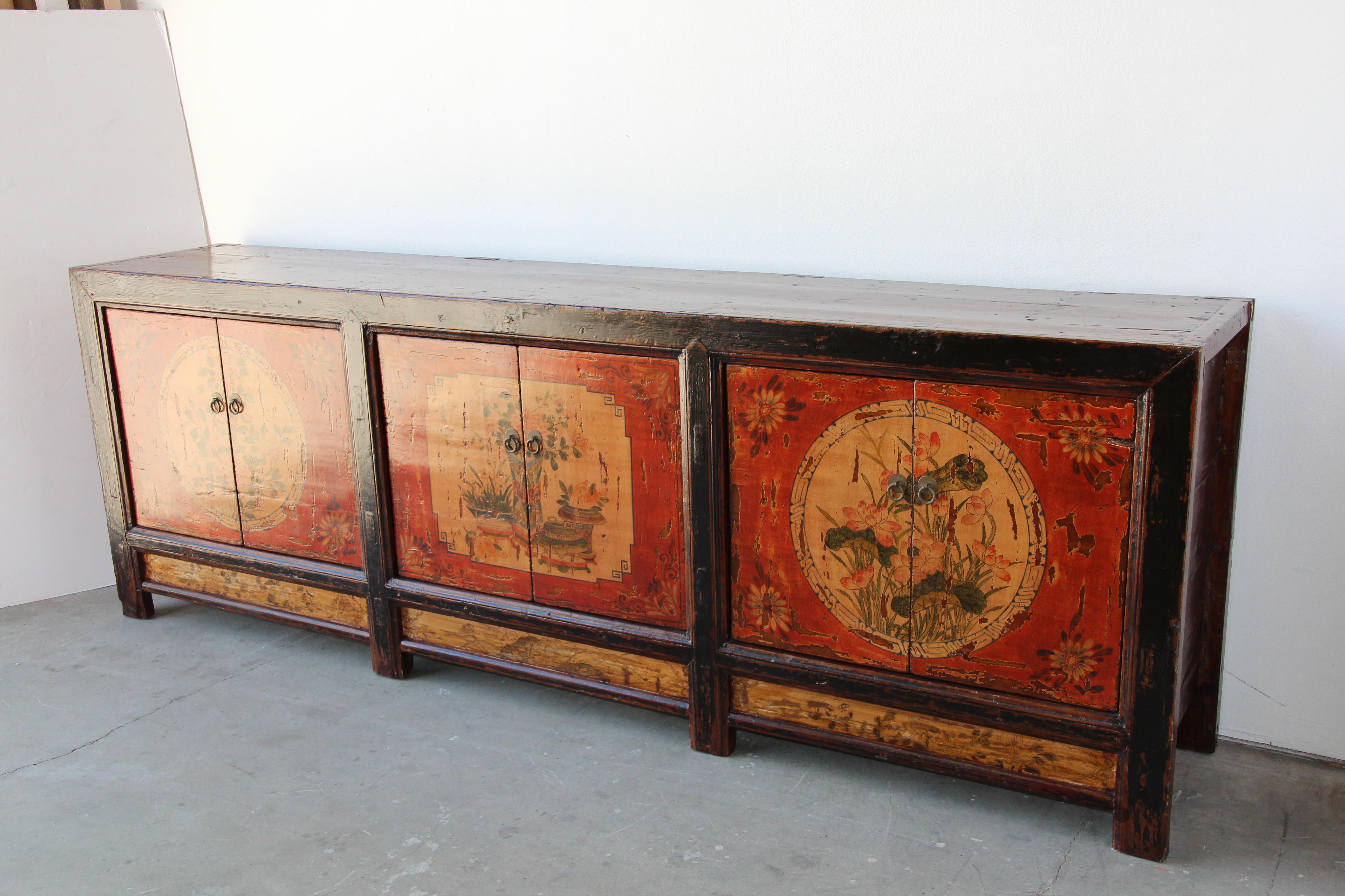 Handcrafted Mongolian sideboard in polychrome floral designs hand painted in front.
Mongolian painted storage cabinet or sideboard. 
Very elegant Bohemian style with simple lines, distressed antique look.
Floral design hand painted in rich red,