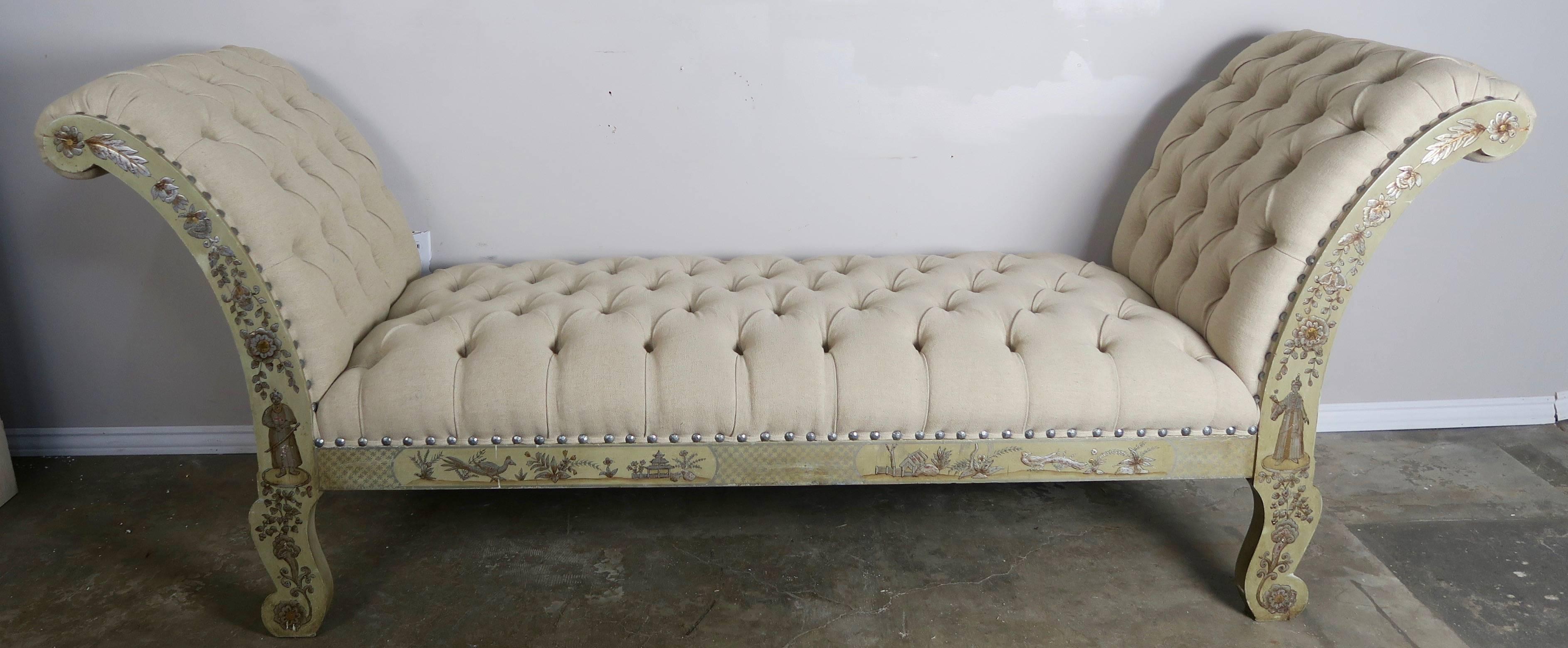 This painted celadon colored bench has gold and silver raised chinoiserie decoration throughout depicting figures, flowers, birds and architecture. The bench is upholstered in a oatmeal colored Belgium linen nailhead trim detail. The bench is