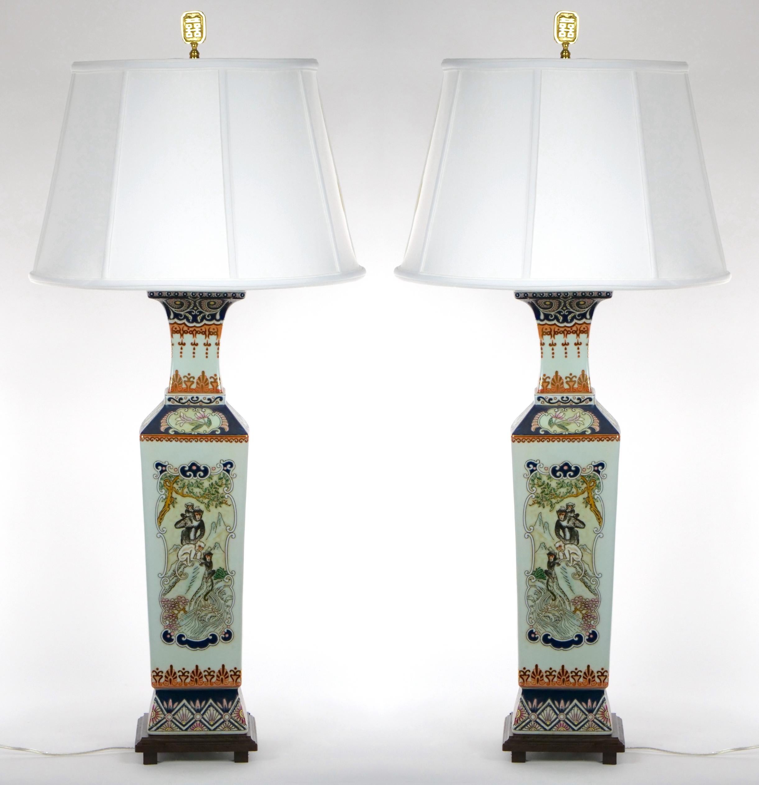 Beautifully hand painted and decorated Chinoiserie scene details glazed porcelain pair table lamp. Each lamp features a different motif of monkeys , foliate and floral scene background on each side resting on a square footed base. Each lamp is in