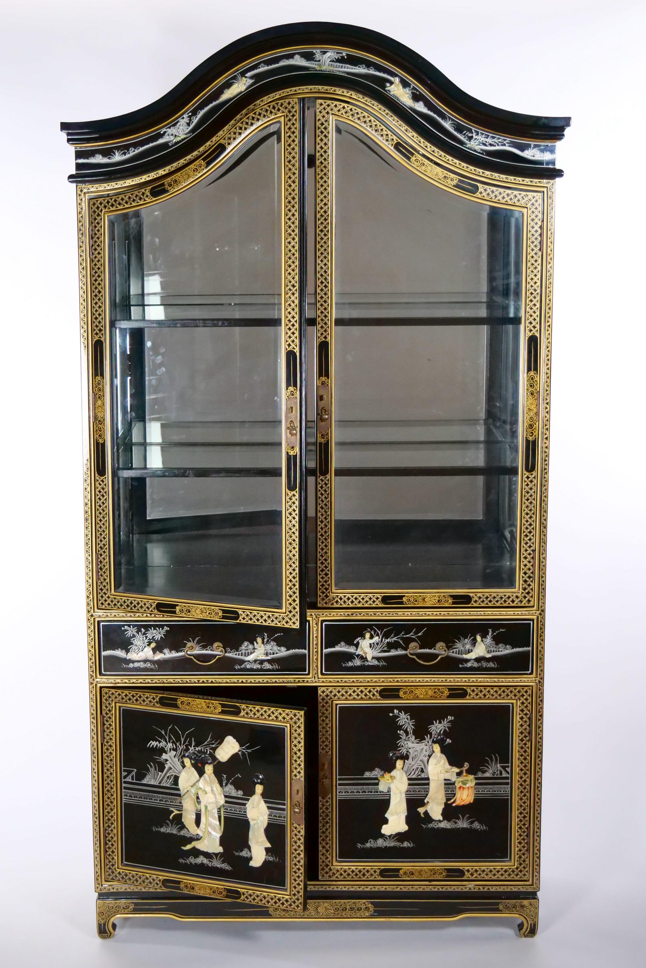 Beautifully hand painted and decorated black lacquered giltwood chinoiserie scene detail display china cabinet. The cabinet / vitrine features a double top front door with two attached wood framed glass shelves resting on two pull front drawers