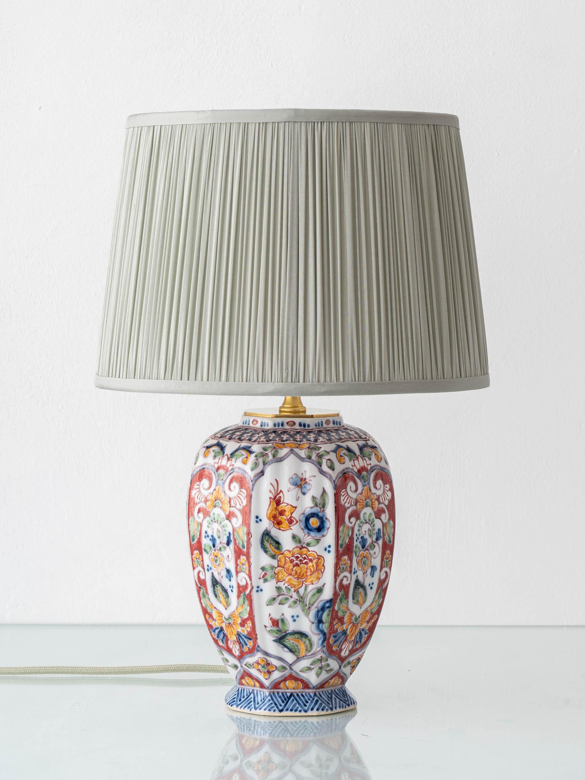 In sorgfältiger Handarbeit vom Amitābha Studio aus einer antiken Altena & Krooyenga Makkum (Niederlande, Mitte des 20. Jahrhunderts) Steingutvase - handbemalt im polychromen Delfter Stil - mit einem gefalteten Seidenlampenschirm in hellem Salbeigrün