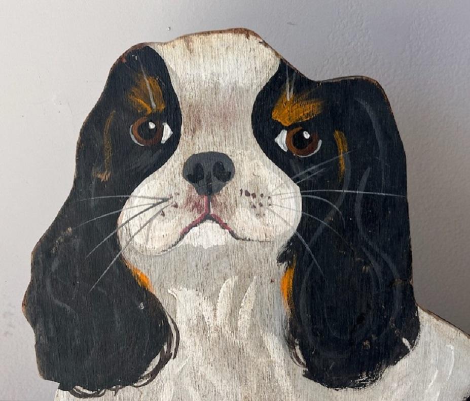 Cette peinture de chien sur carton, à l'allure folâtre et amusante, possède un support pliable au verso. Elle est également signée par l'artiste D.Buttler et datée de 1989. Panneau fantastique et folklorique pour un grand chien.