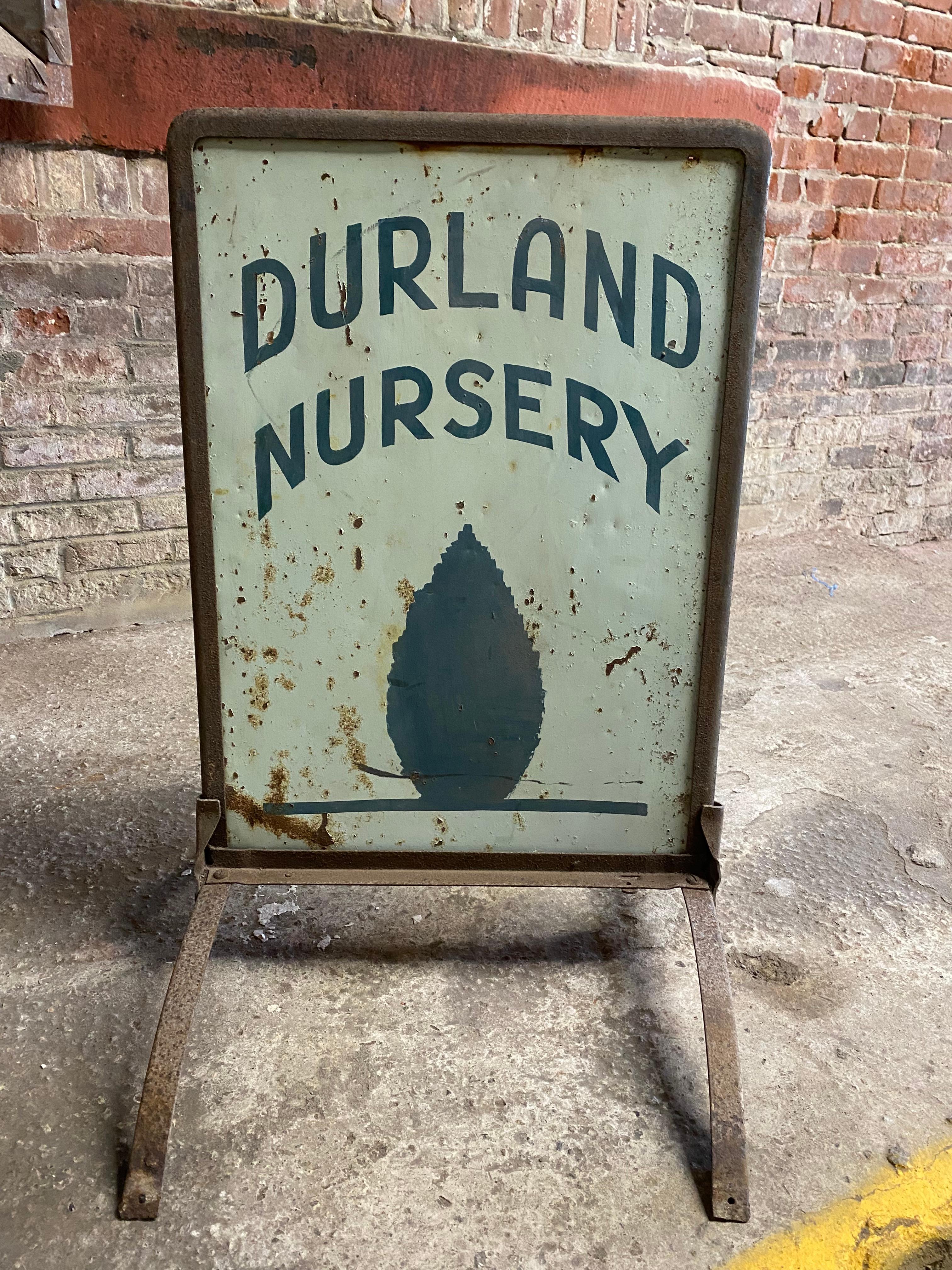 Hand painted double sided sheet metal and iron frame Durland Nursery sign. Circa 1930. Durland Nursery and a lone Evergreen are depicted on either side of this free standing sign. Light green background with dark forest green lettering. A nice