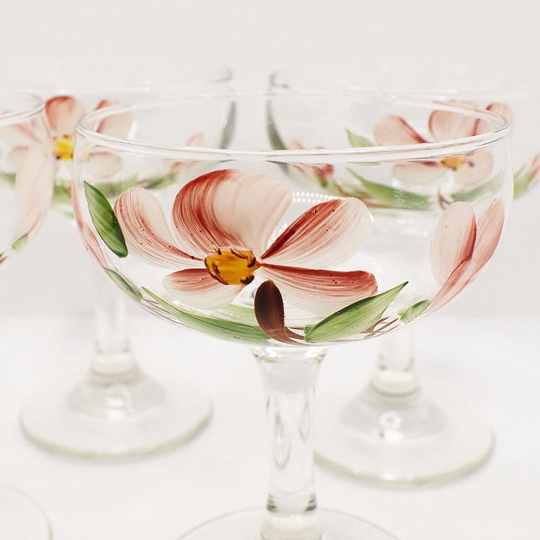 A set of 4 champagne coupe cocktail glasses with hand-painted pink flowers. Add a touch of feminine elegance to your next dinner party or brunch with this set of pretty glasses. Each glass is hand-painted with pink flowers with lush green leaves.