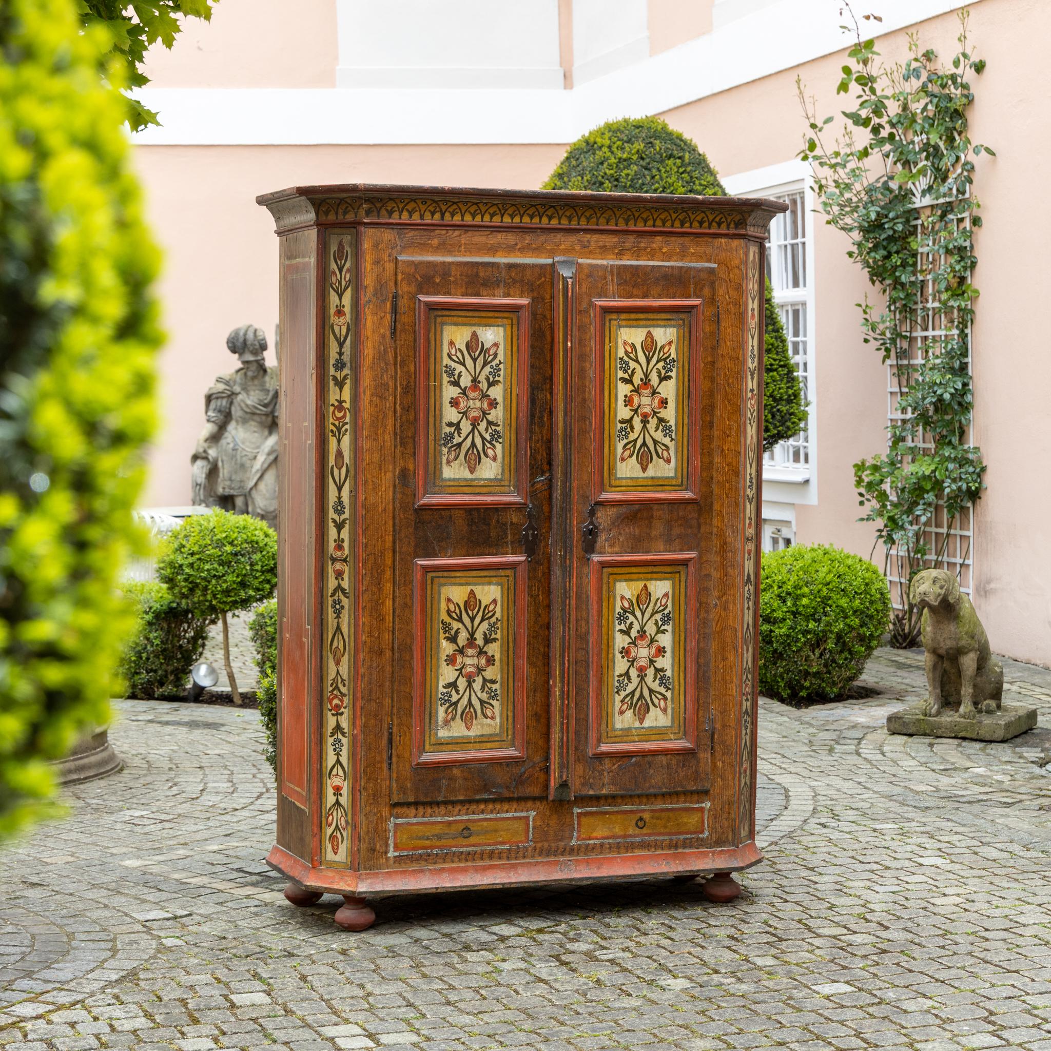 Armoire popolare a due ante con decorazione originale policroma floreale sui pannelli delle ante e sui montanti verticali. I quattro pannelli centrali presentano motivi floreali simmetrici su uno sfondo chiaro, incorniciati da modanature dipinte di