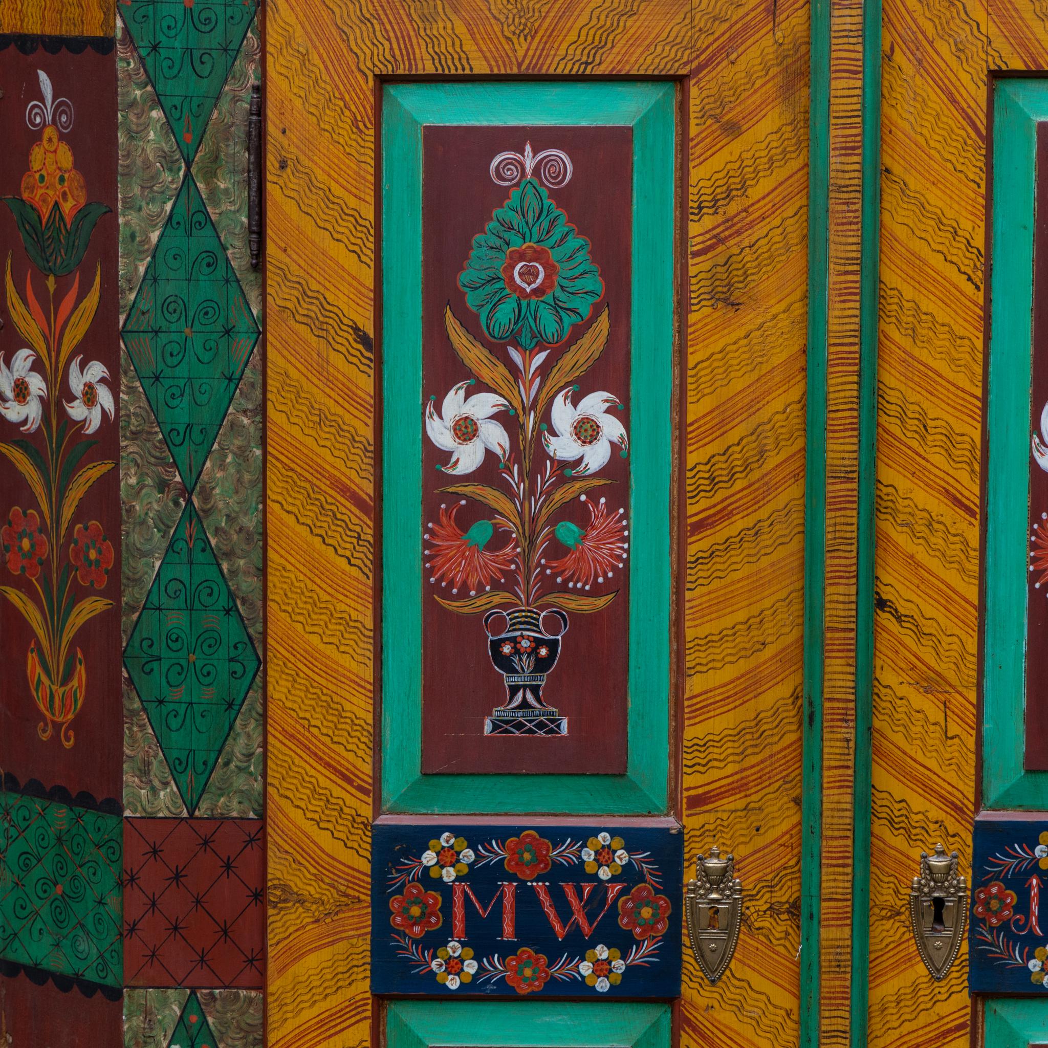 Armadio folk a due ante con un vivace dipinto floreale tradizionale dai colori intensi. Sulle porte sono incisi il monogramma MW e la data 1851. Un autentico esempio di artigianato rurale del XIX secolo proveniente dalla Germania meridionale.