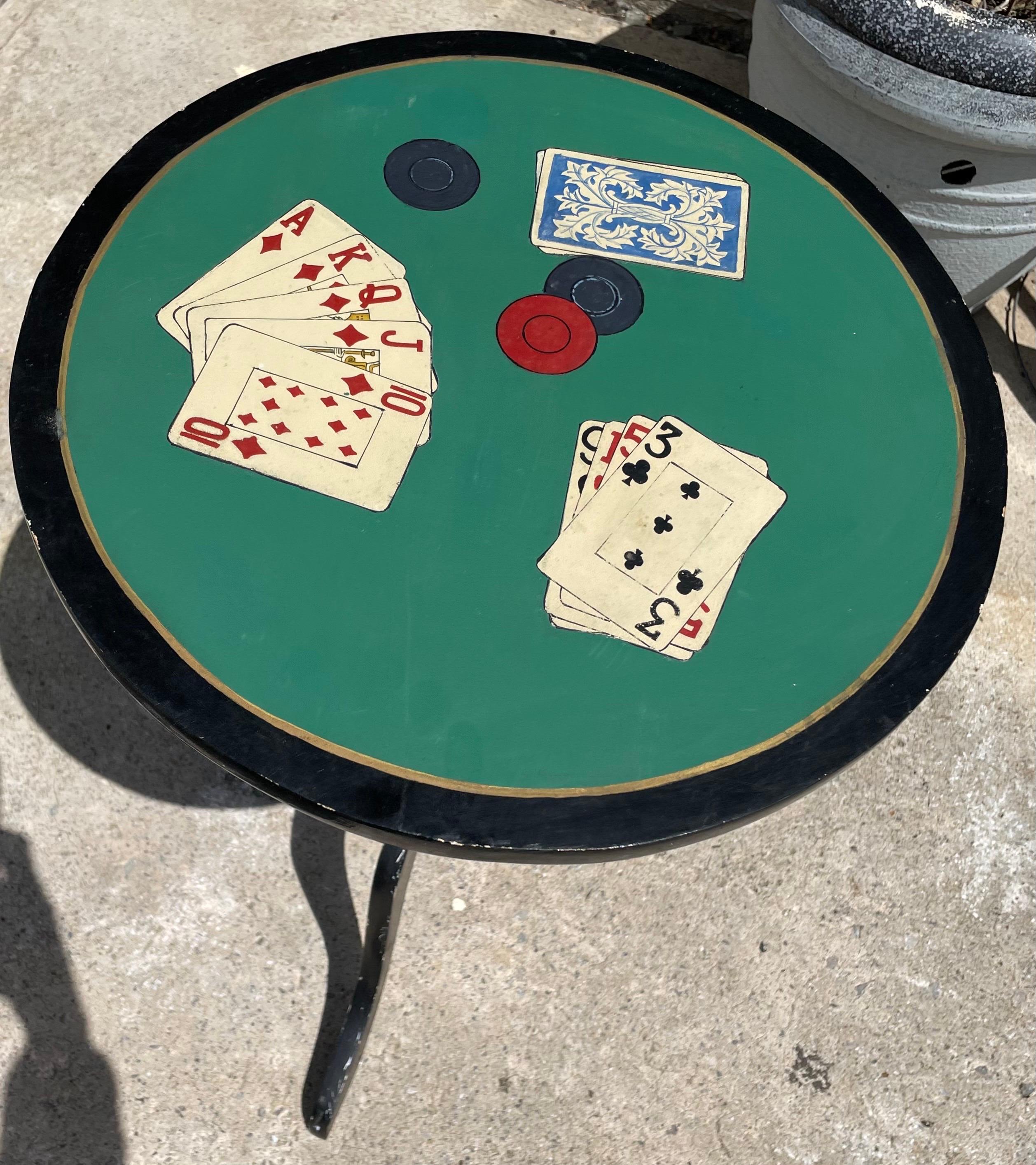 Ecco un'adorabile bancarella, dipinta in fabbrica di un nero lucido con riflessi dorati sulle curve in rilievo, che un artista di talento ha adornato con un piano in feltro verde e due mani di carte da gioco, oltre al mazzo rovesciato e ad alcune
