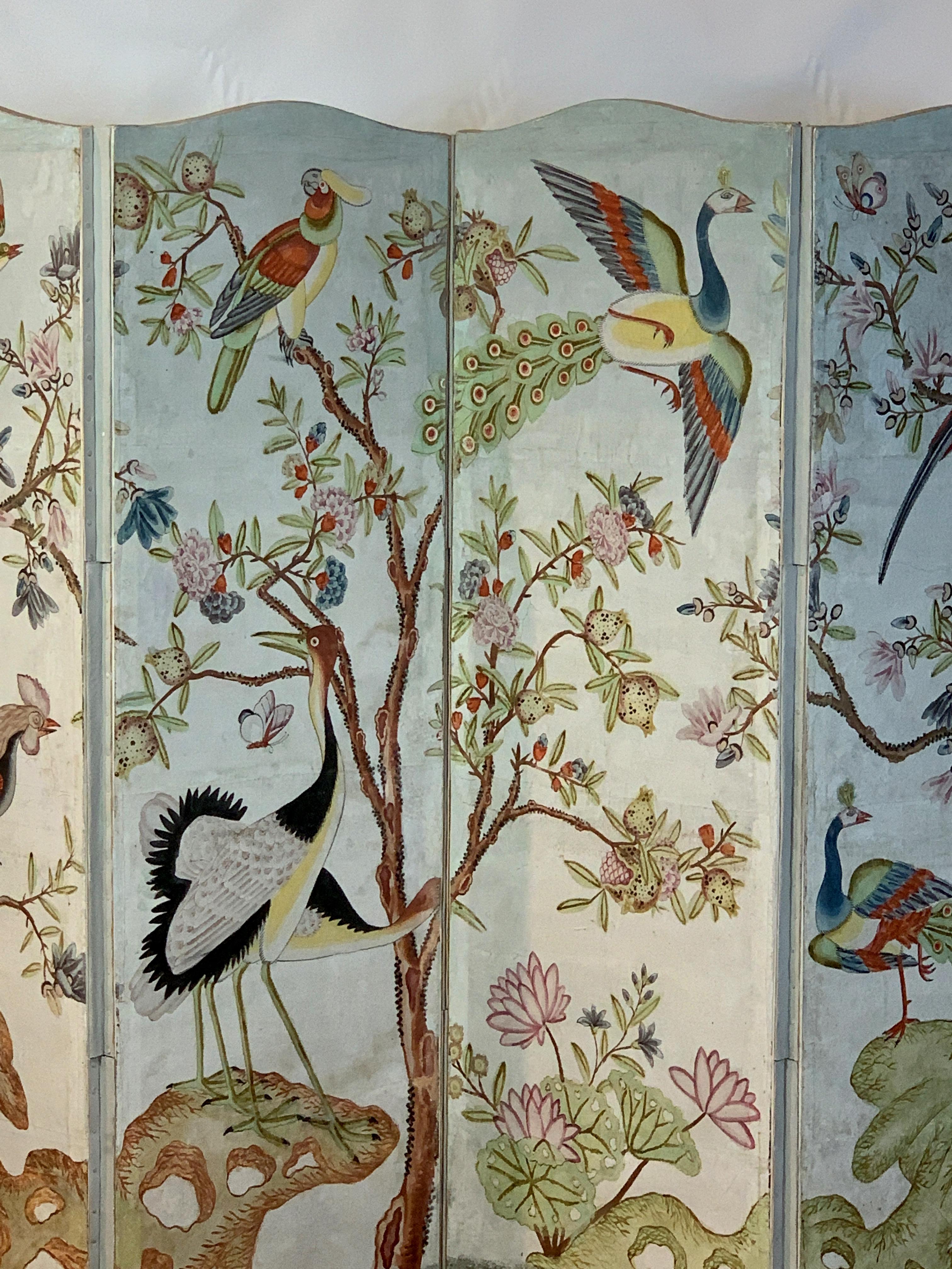 A beautifully painted early 20th century four panel folding screen in the style of Gracie or de Gournay wallpaper depicting exotic colorful birds set amid flowering trees.