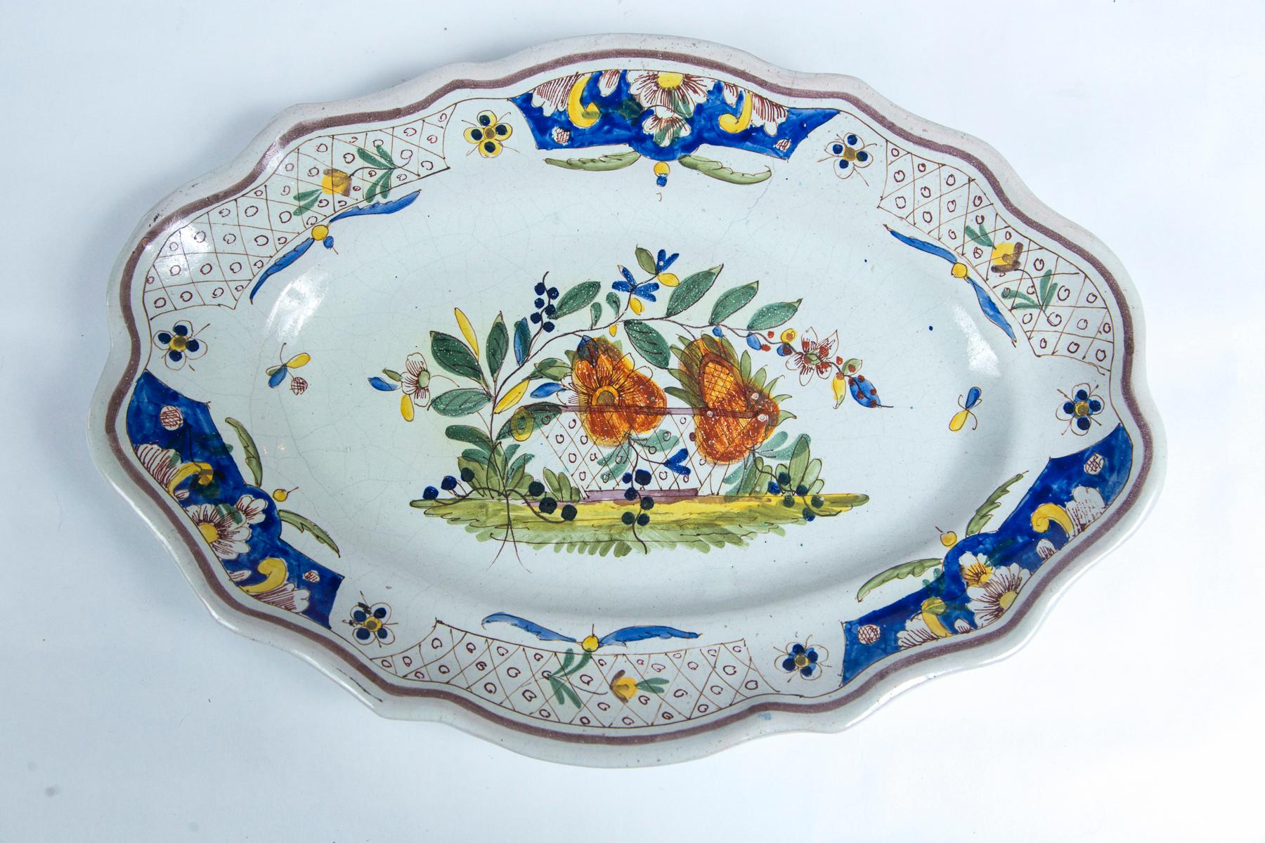 Hand painted French faience platter, early 19th century. Scalloped, oval shape. Center floral and border designs in traditional coloration.