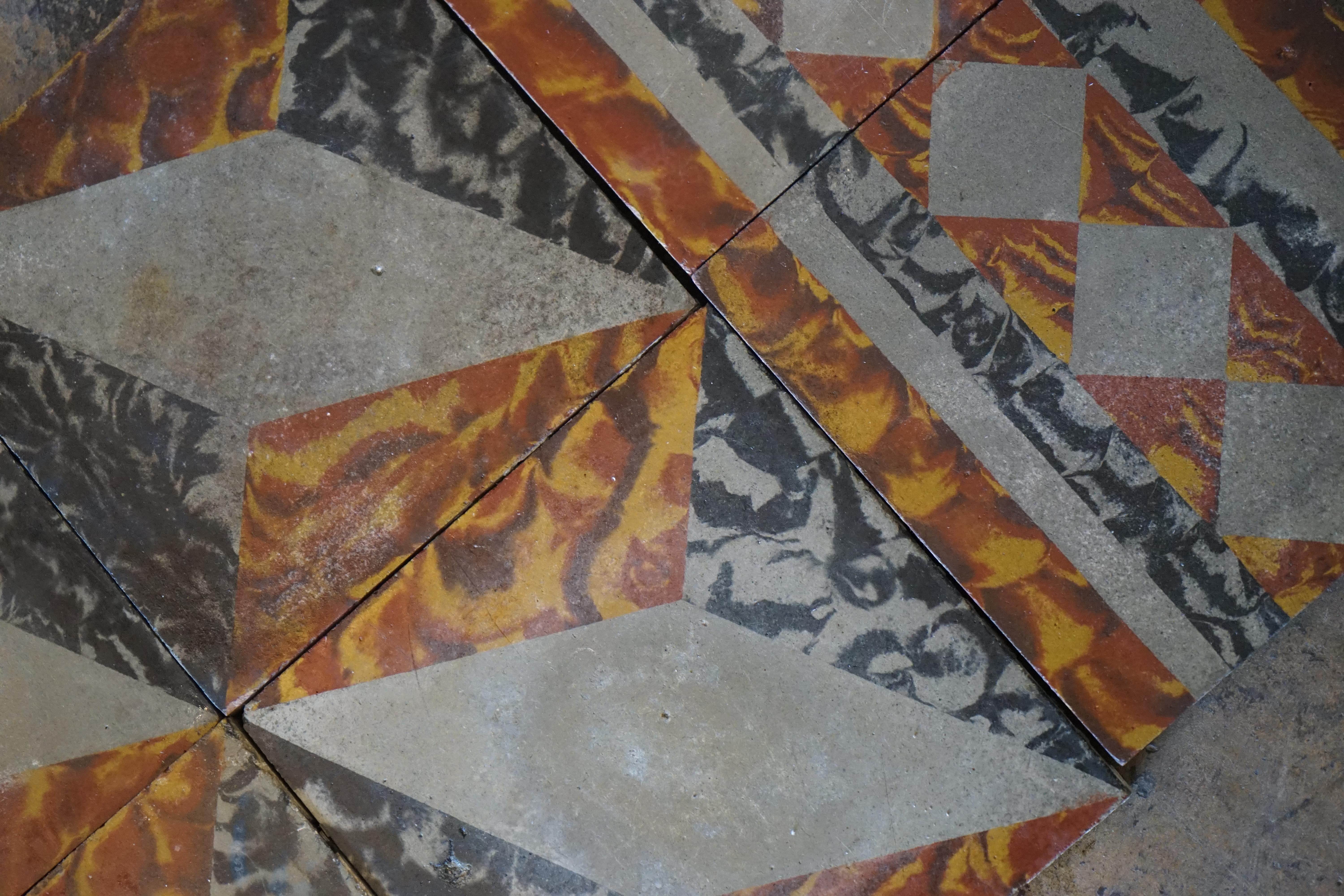 This lot of reclaimed tiling originates from France circa the 1920s. Features a vibrant patterned design of orange, yellow, and black painterly strokes on grey concrete. 

125 square feet with approximately 30 square feet of border tile.

Each tile