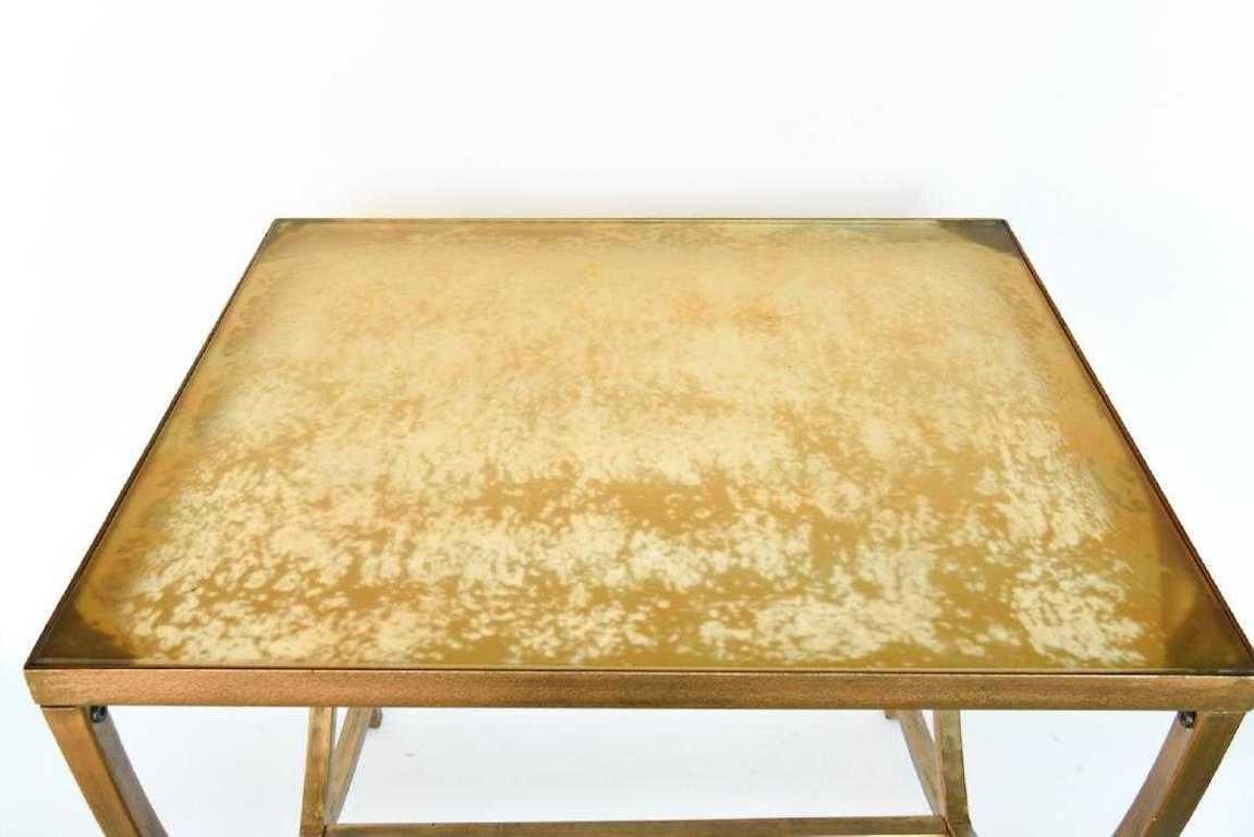 A hand painted gold metal and glass side table in the Art Deco style. The conforming hand painted top rests on U-shaped bases at either end with a cross-stretcher for support and terminates in rectangular brass feet. Contemporary. Dimensions: H 22